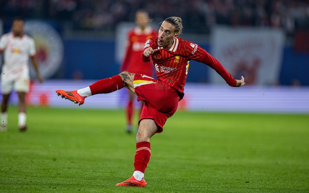 Soccer player in red and yellow uniform kicking the ball in a stadium.