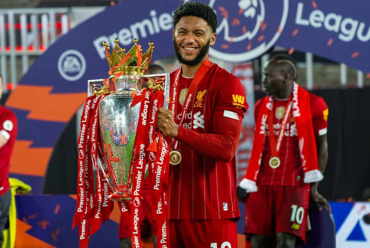 Soccer player holding Premier League trophy, wearing a red uniform, with a medal around his neck.