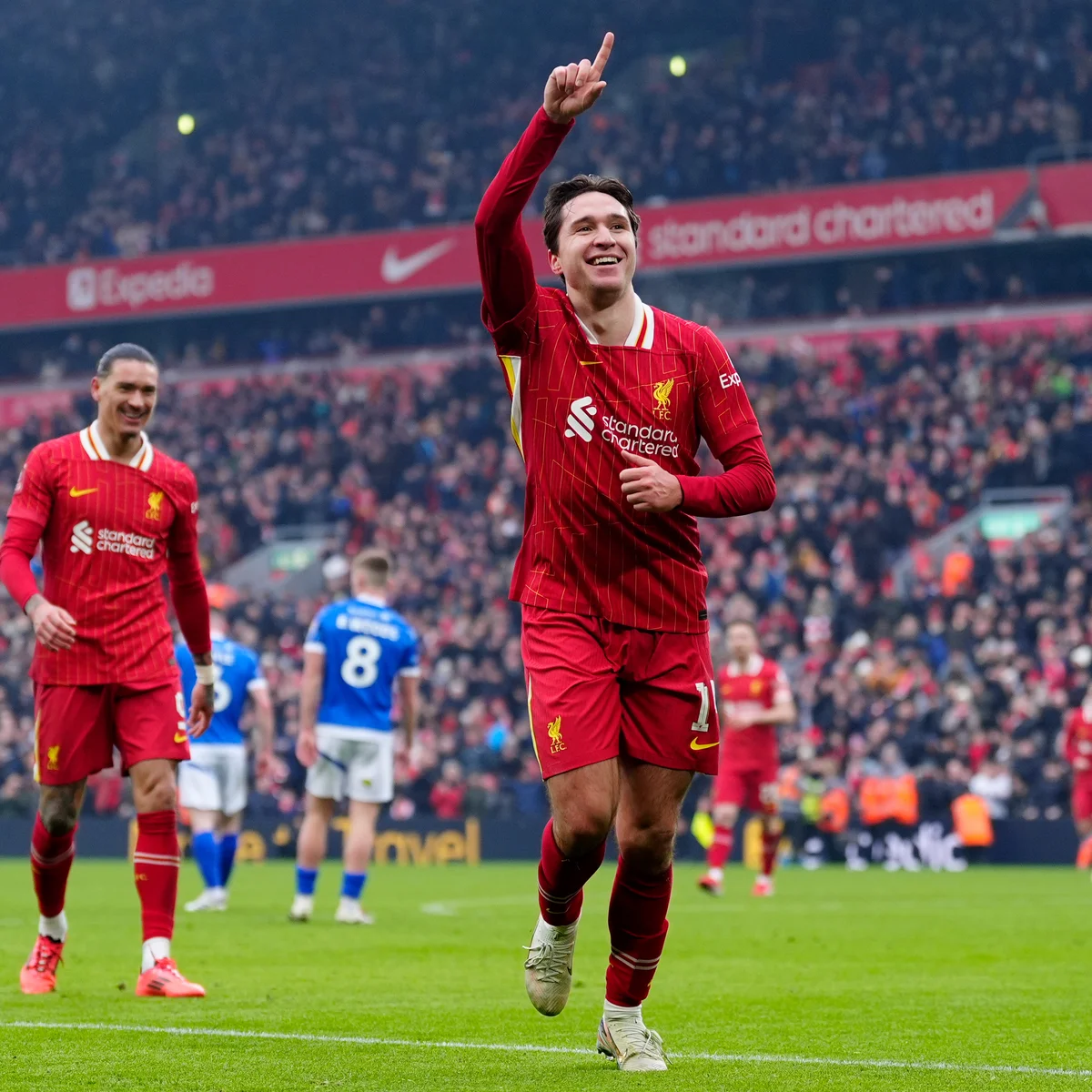 Soccer player in red jersey celebrating a goal on a field, with cheering crowd in the background.