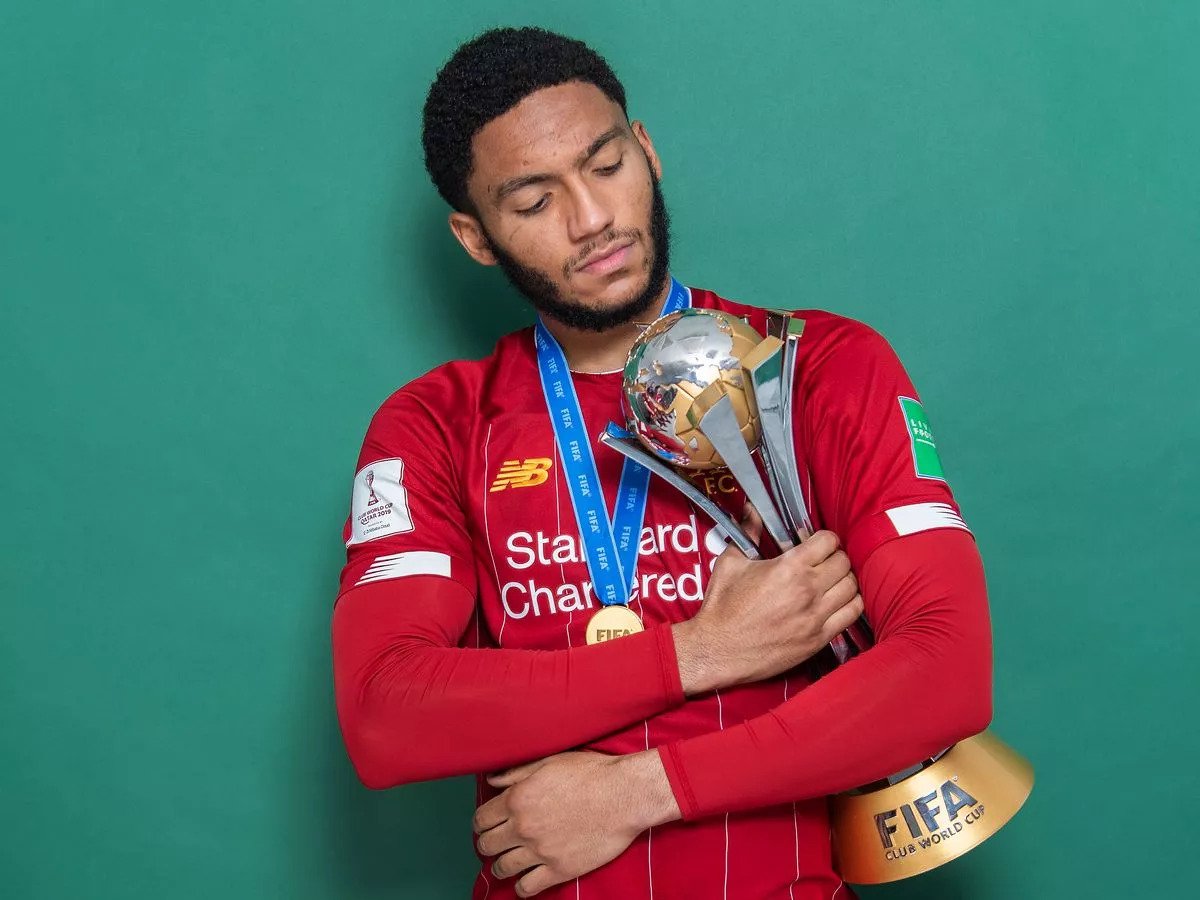 Soccer player in a red jersey holding a FIFA Club World Cup trophy with a blue winner's medal.