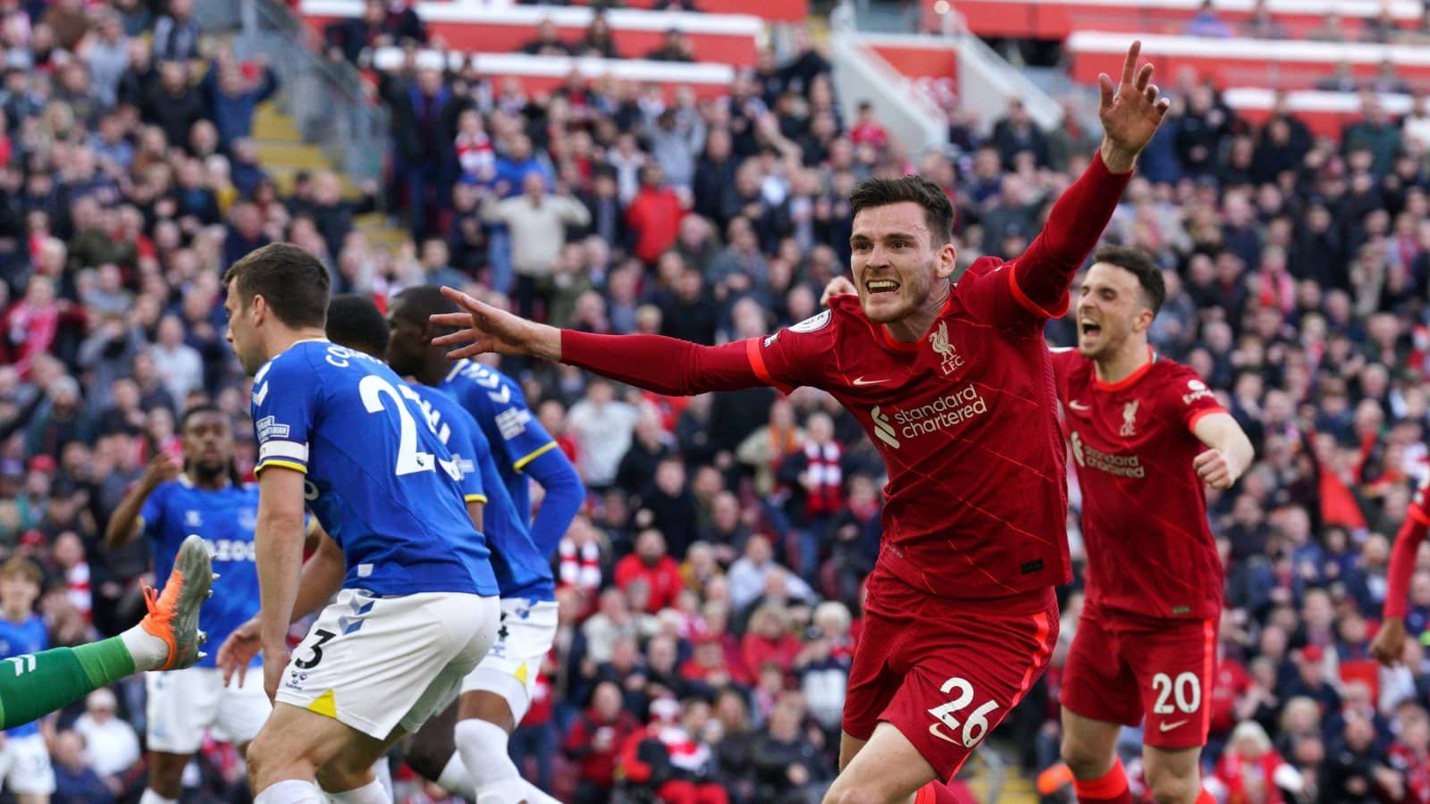 Soccer player in a red kit celebrating during a match with a crowd in the background.
