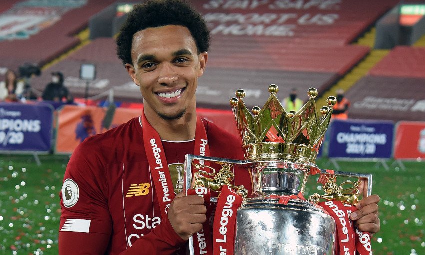 Soccer player holding Premier League trophy in stadium.