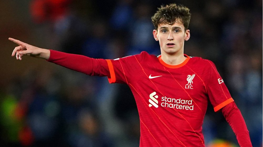 Soccer player wearing a red Liverpool FC jersey gesturing with his right arm extended during a match.