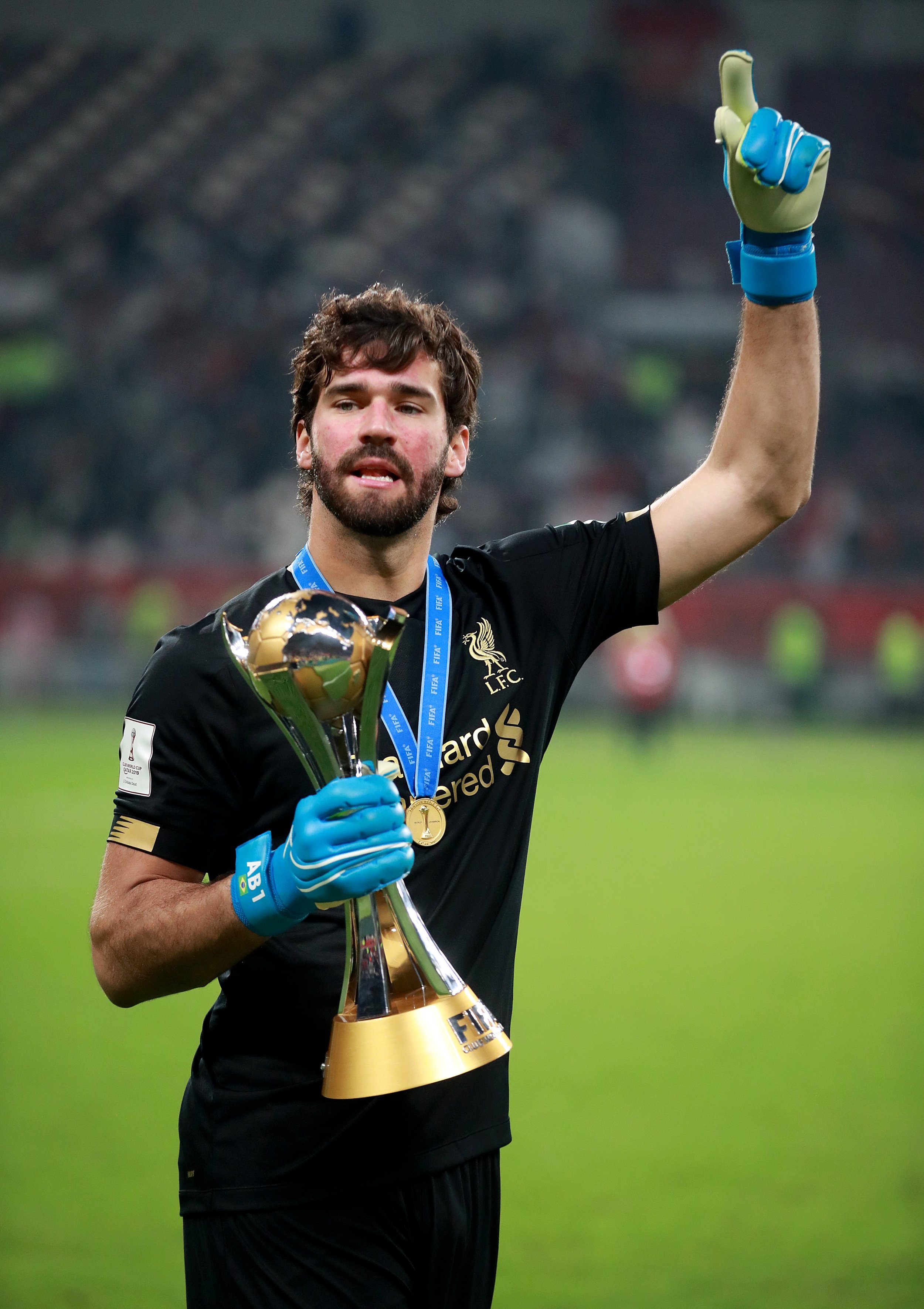 Soccer player in black uniform holding a FIFA trophy.