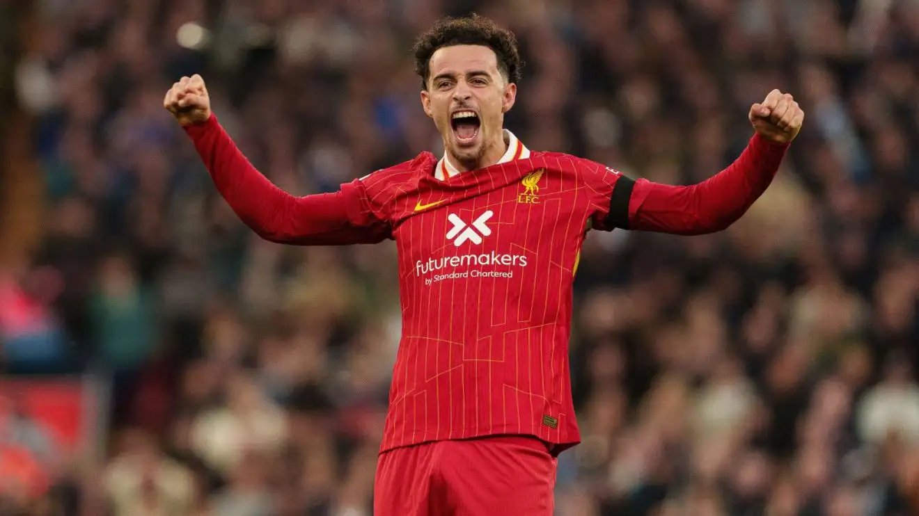Soccer player in red jersey celebrating with arms raised.