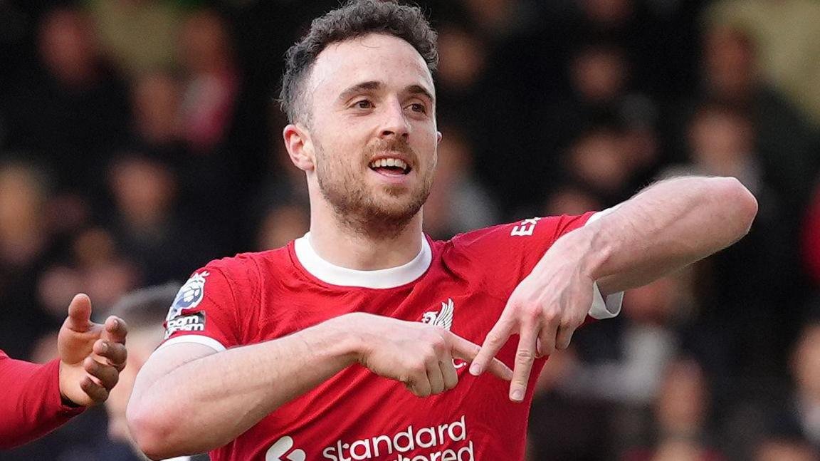 Soccer player in red jersey gesturing a celebration on a field.