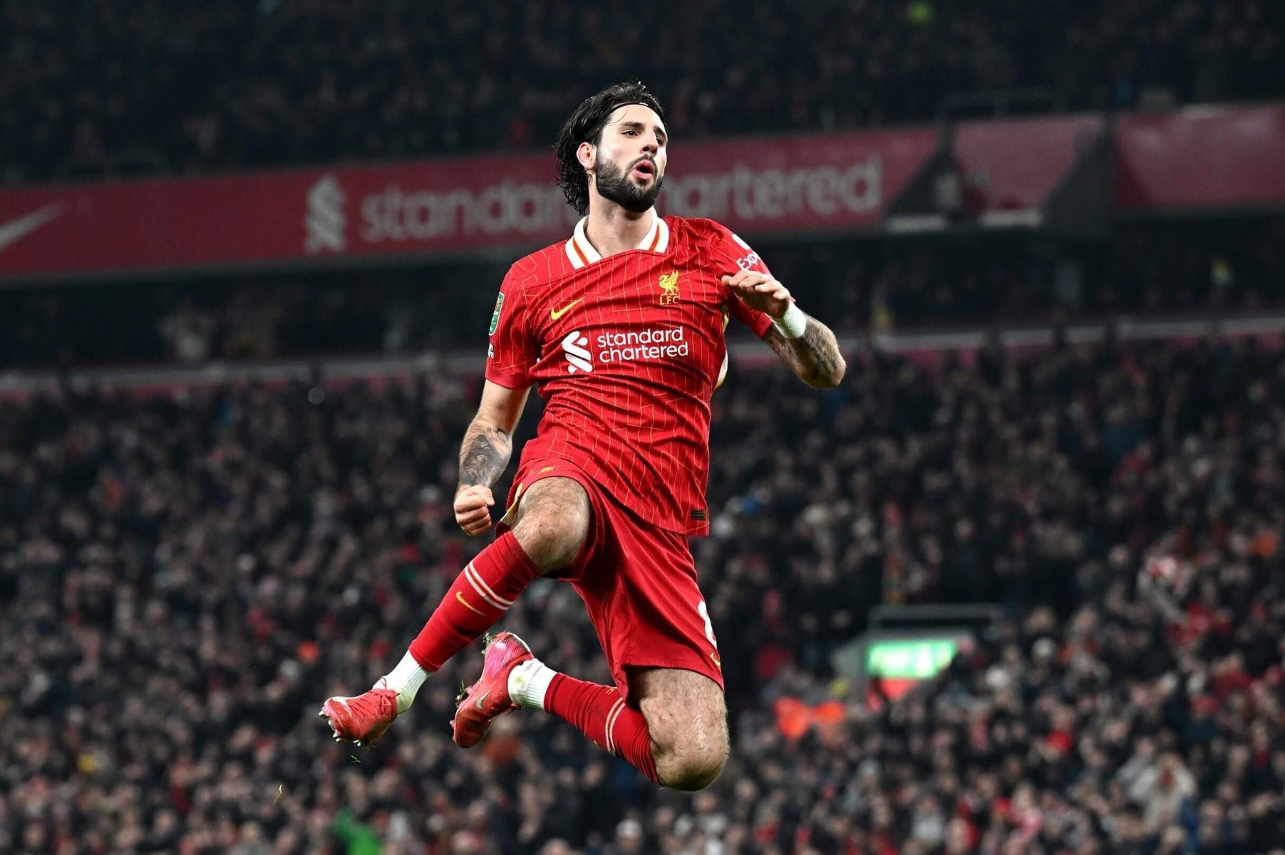 Soccer player in red Liverpool jersey celebrating in stadium