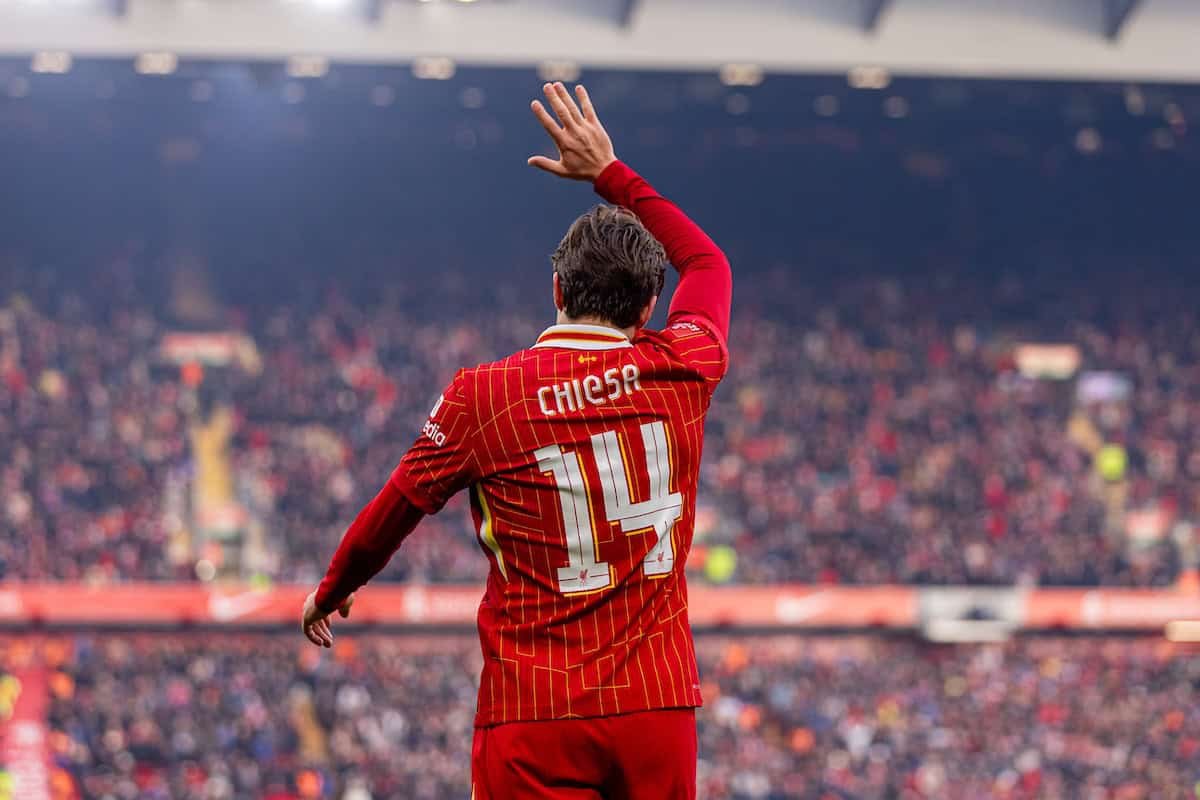 Soccer player in red uniform with number 14 waving to crowd in stadium.