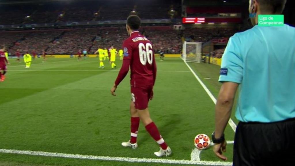 Soccer player preparing for a corner kick during a match, wearing a red jersey with the number 66, while a referee stands nearby.