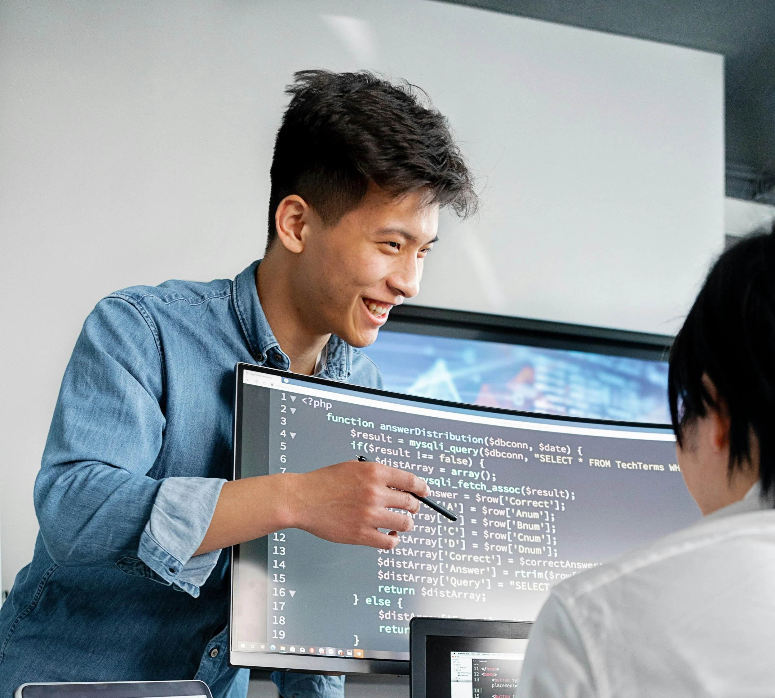 Jóvenes programadores trabajando en un proyecto de programación en una oficina, con una pantalla mostrando código."