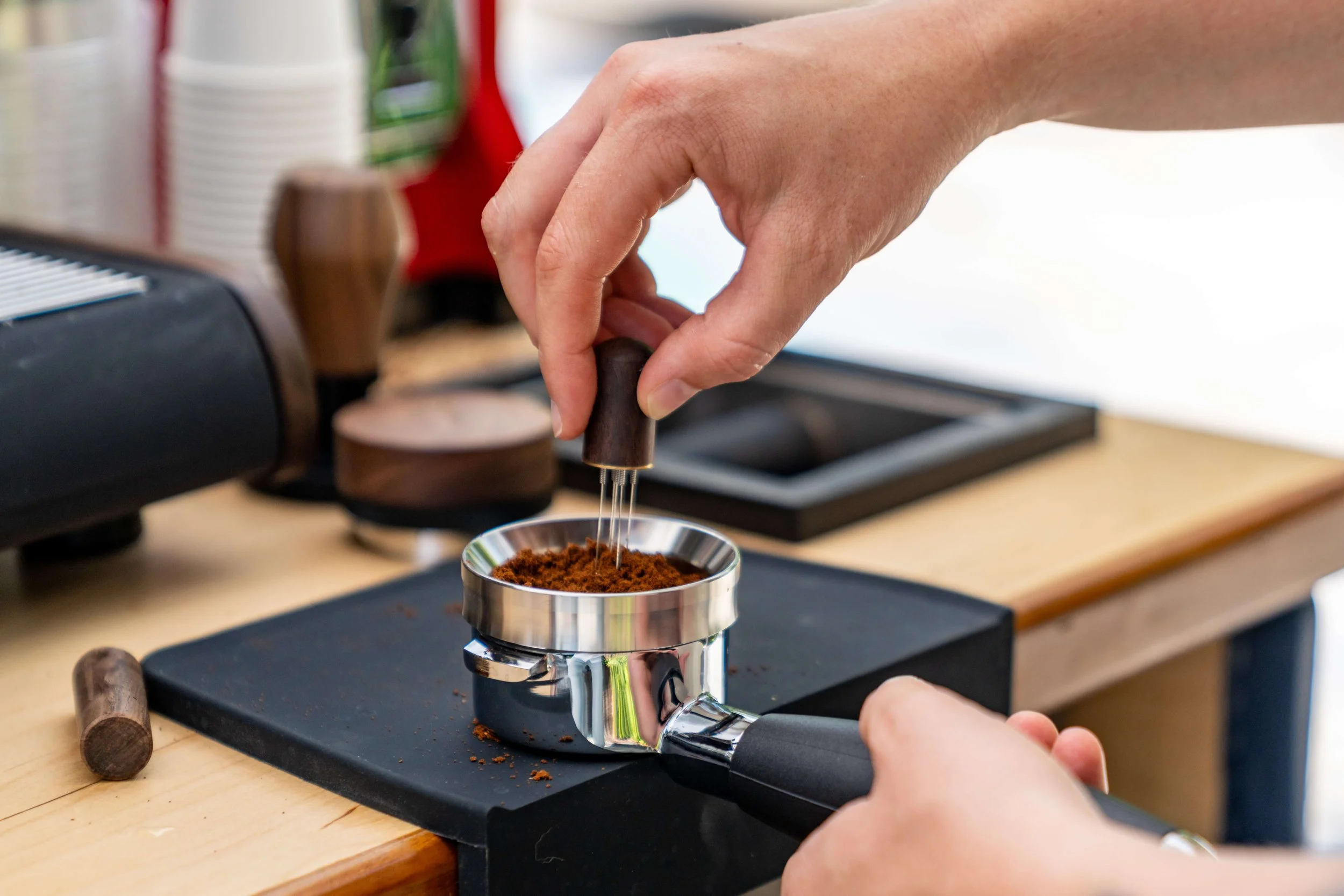 Barista using a WDT tool to declump coffee grounds in a portafilter