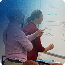 Jennifer Thompson with a client writing and planning on a whiteboard