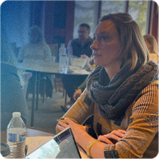 Jennifer Thompson sitting at a table focusing and learning from a speaker.