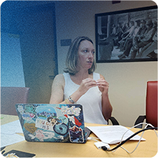 Jennifer Thompson with a laptop in front of her speaking with a client