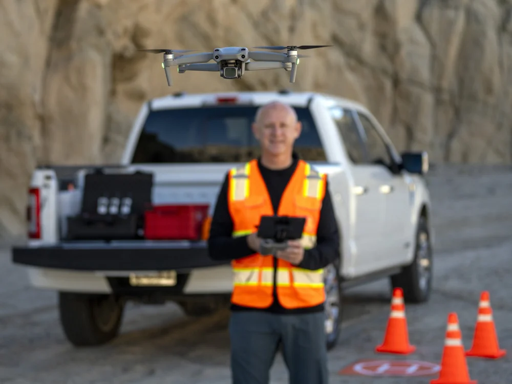 CVUAS pilot in a hi-vis vest with a drone controller beside the field truck at a quarry