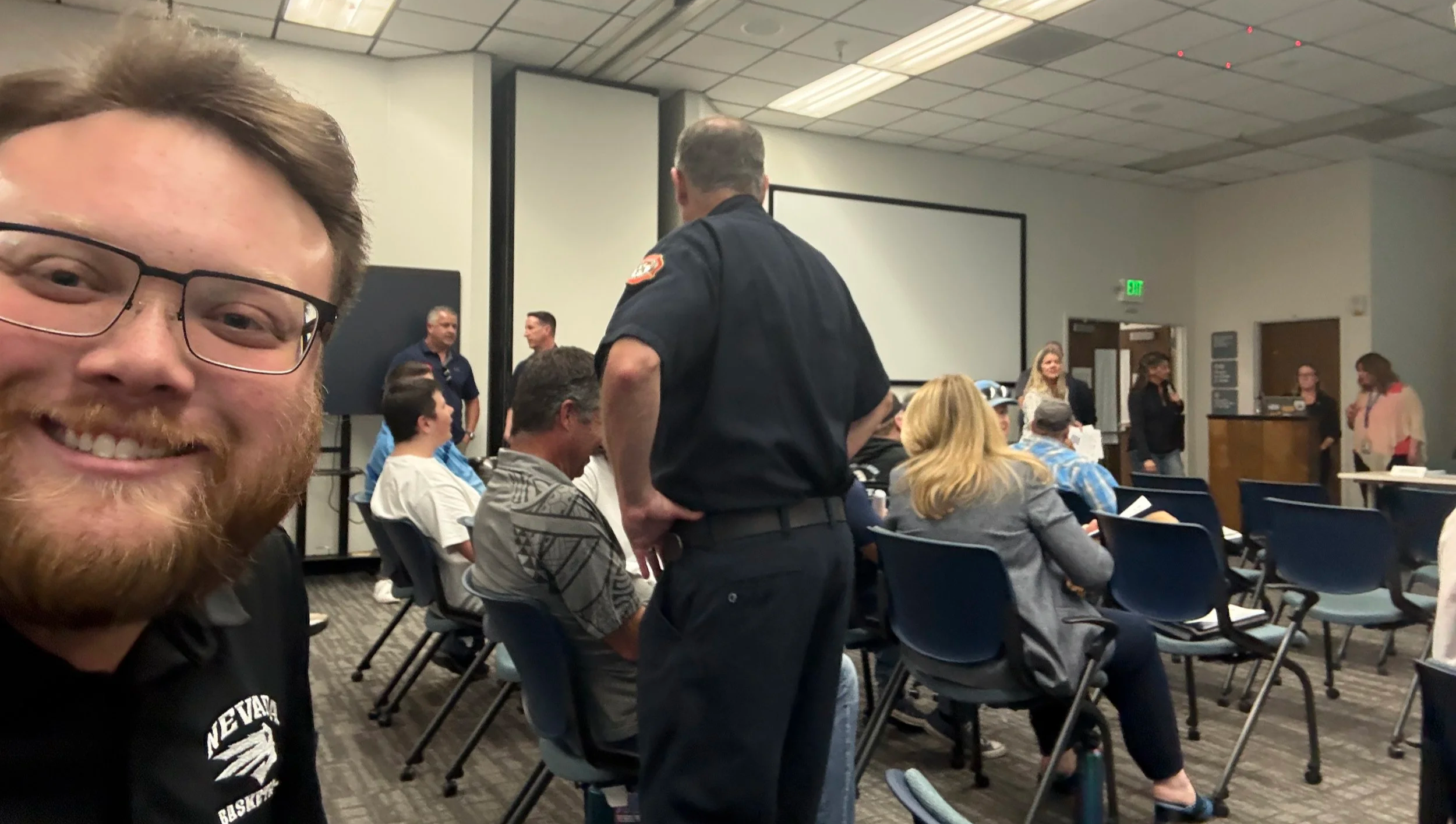 Hunter Rand takes a selfie in the Northern Nevada Public Heath Conference room surrounded by attendees.