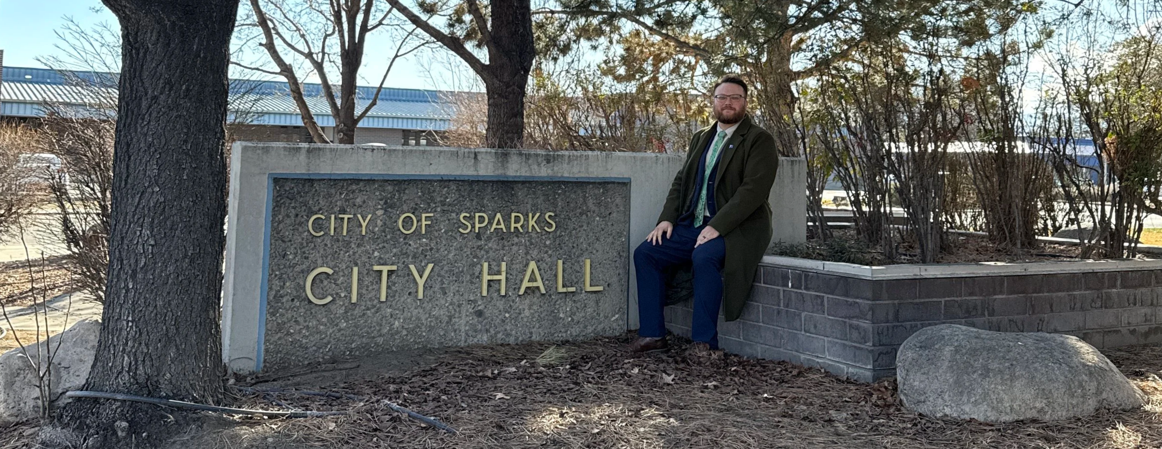 Hunter Rand sits next to the City of Sparks City Hall sign.