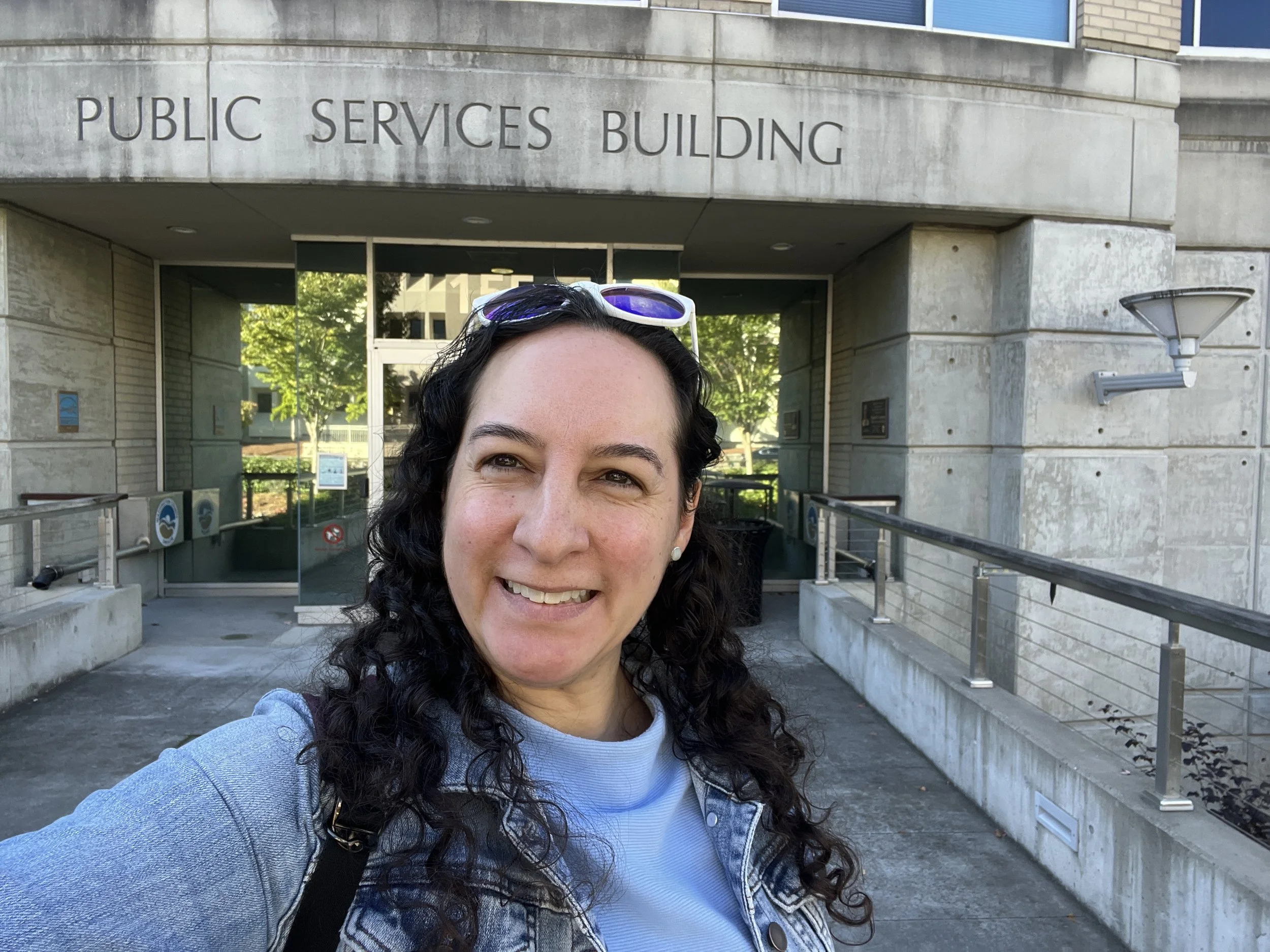 A selfie of Felicita in front of the entrance to the Public Services Building