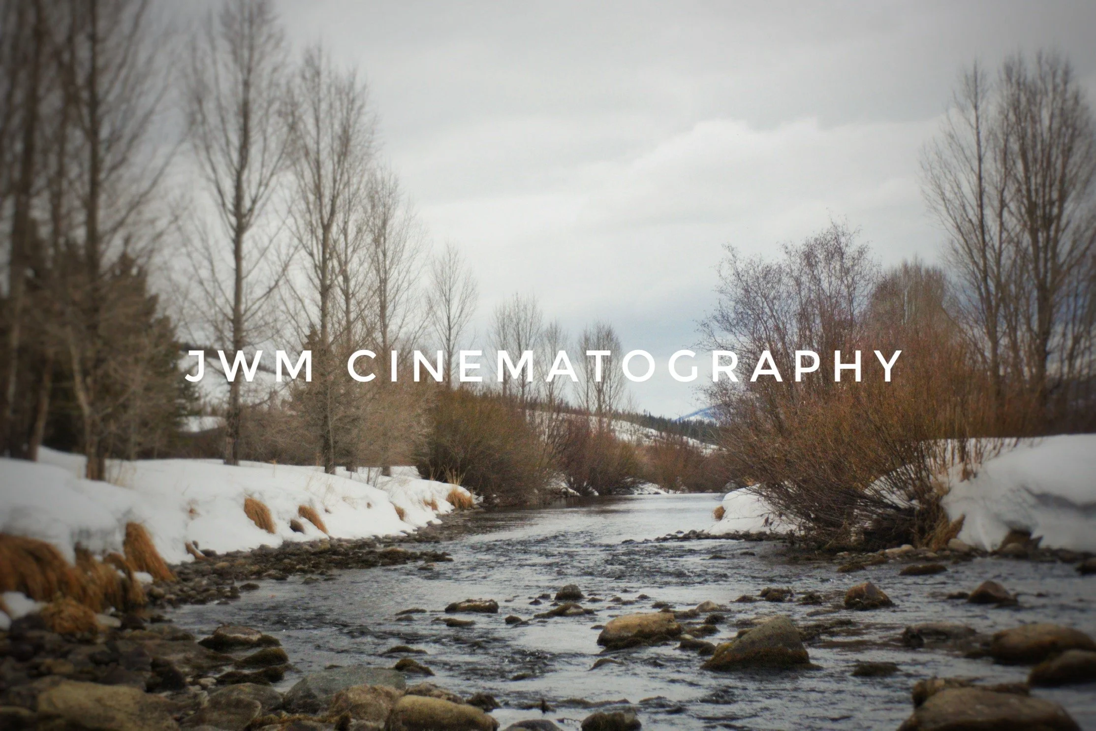 Winter river scene with bare trees and snowy banks, text "JWM Cinematography" overlayed.