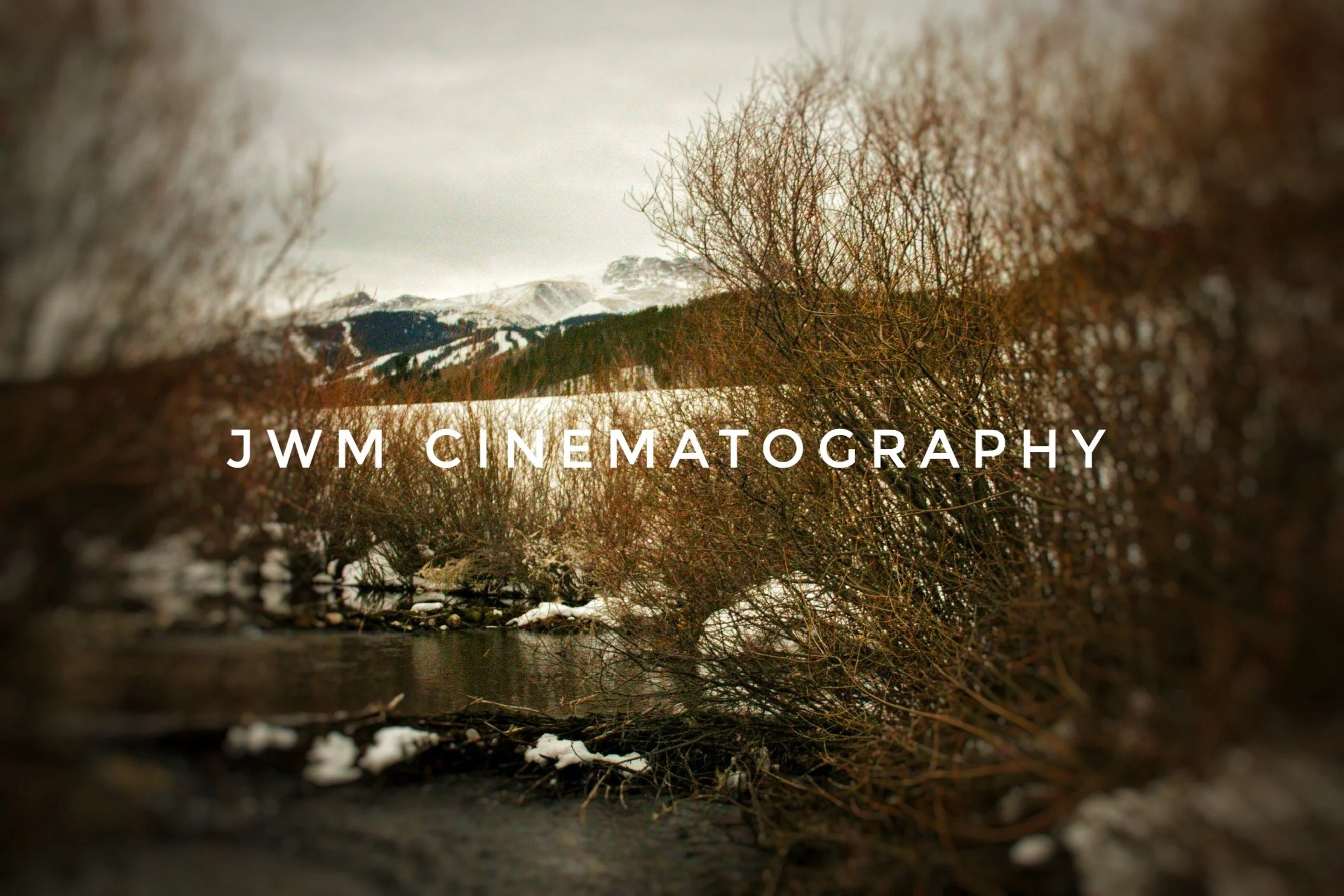 Winter landscape with snowy mountain, bare trees, stream, and text "JWM Cinematography."