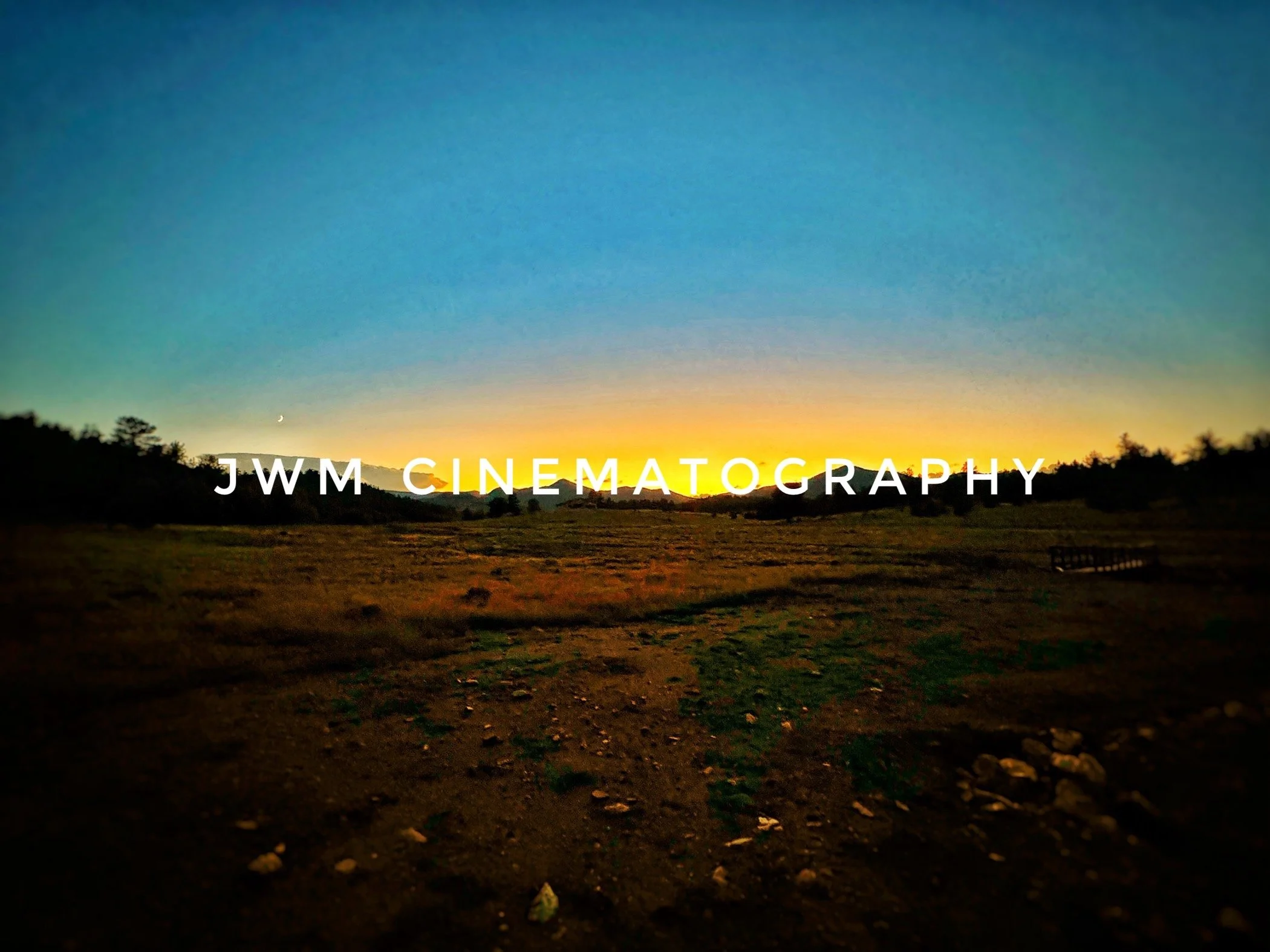 Twilight landscape with "JWM Cinematography" text, featuring a sunset sky over a field and silhouette of trees.