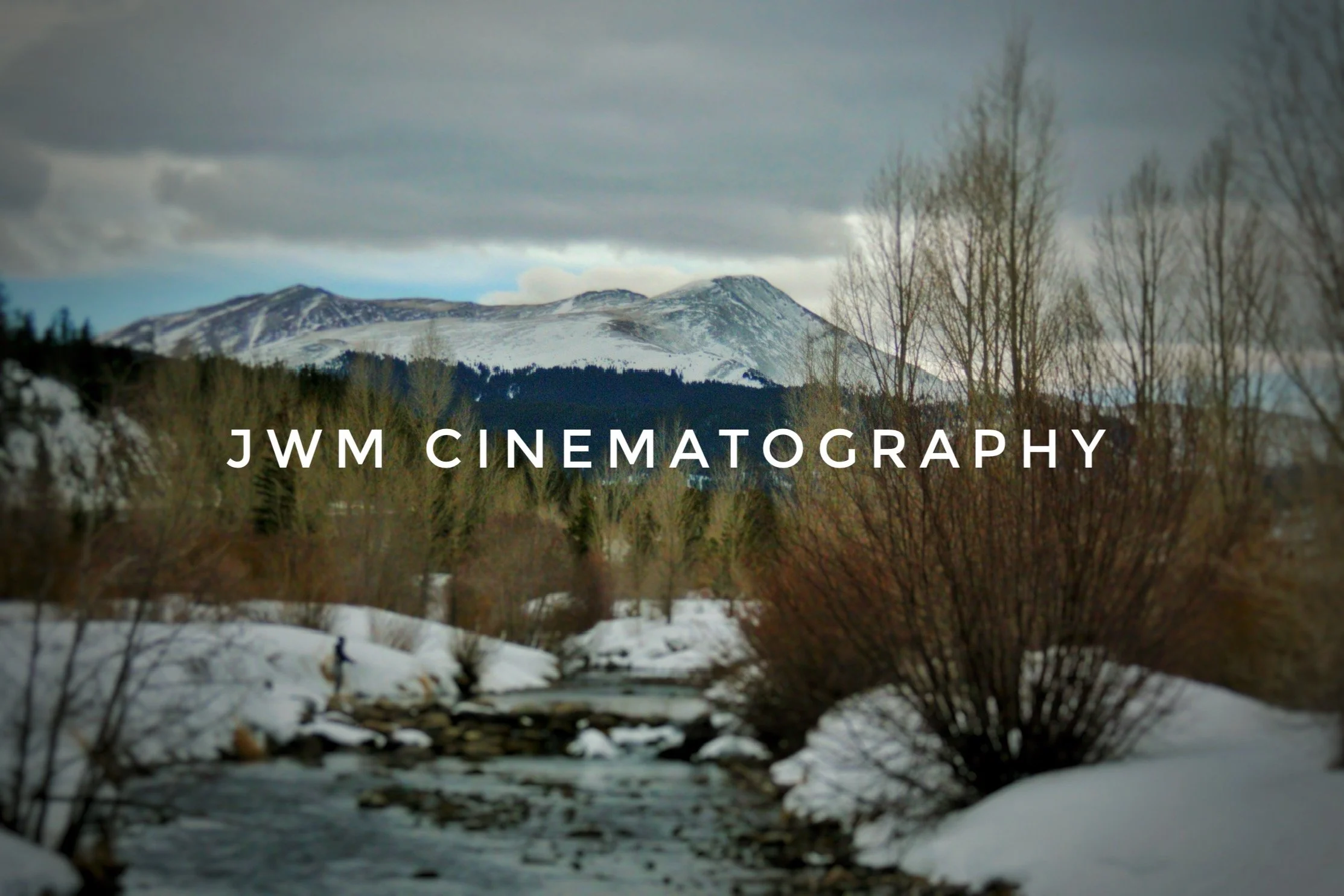Snowy mountain landscape with creek and trees, "JWM Cinematography" text overlay.
