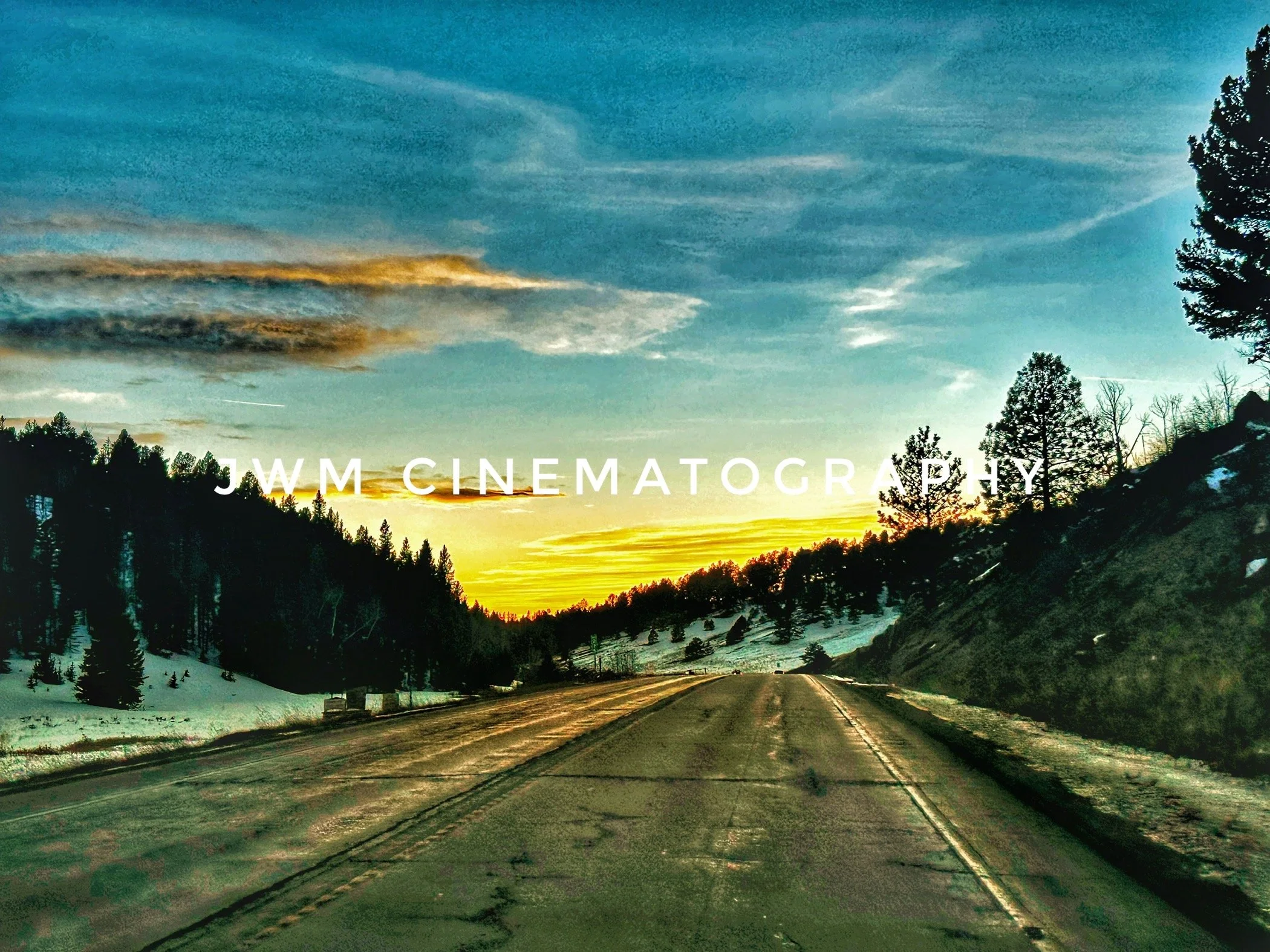 Scenic road at sunset with snow-covered hills and trees, featuring "JWM Cinematography" text.