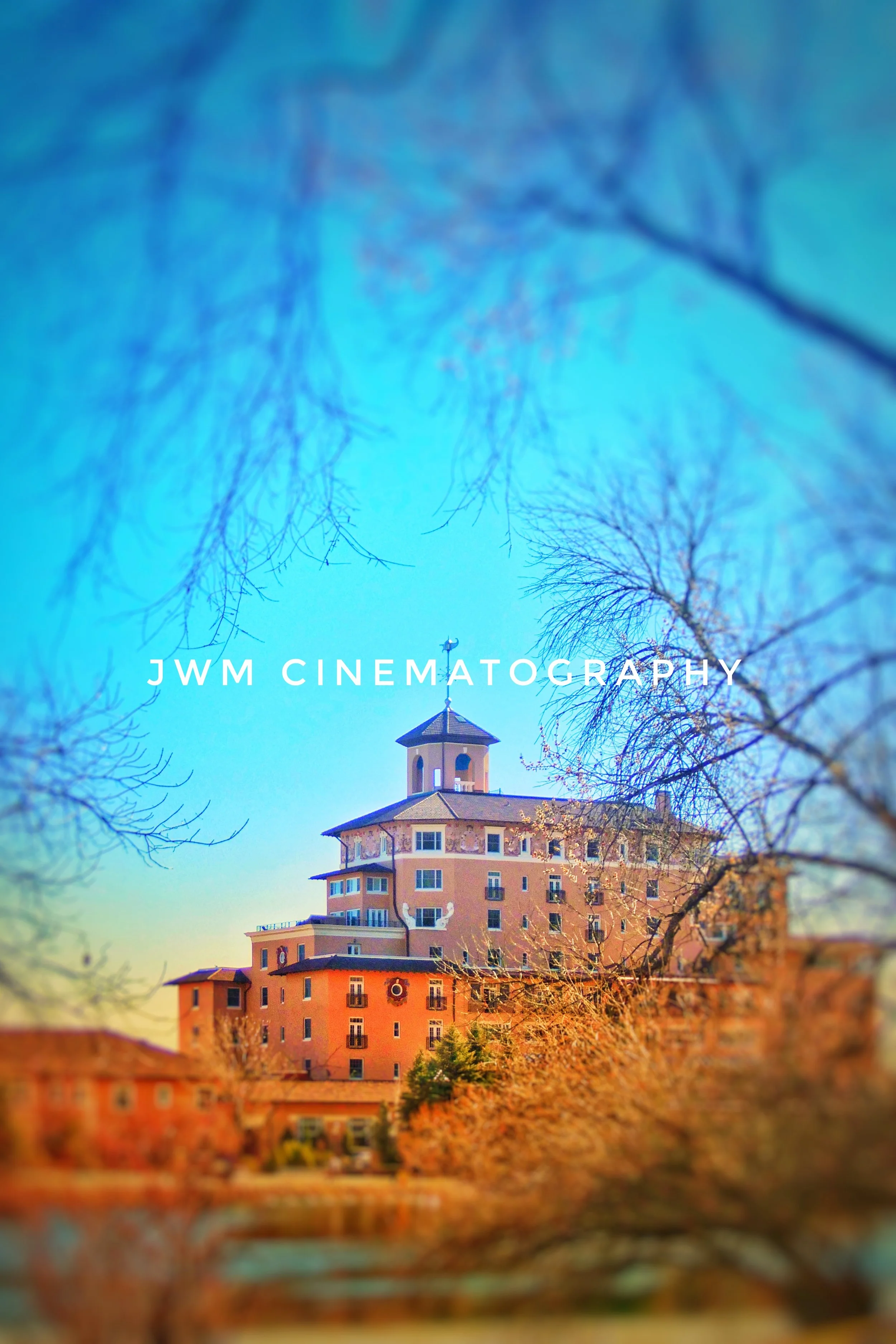 Historic building with a tower and trees in the foreground, featuring text "JWM Cinematography."
