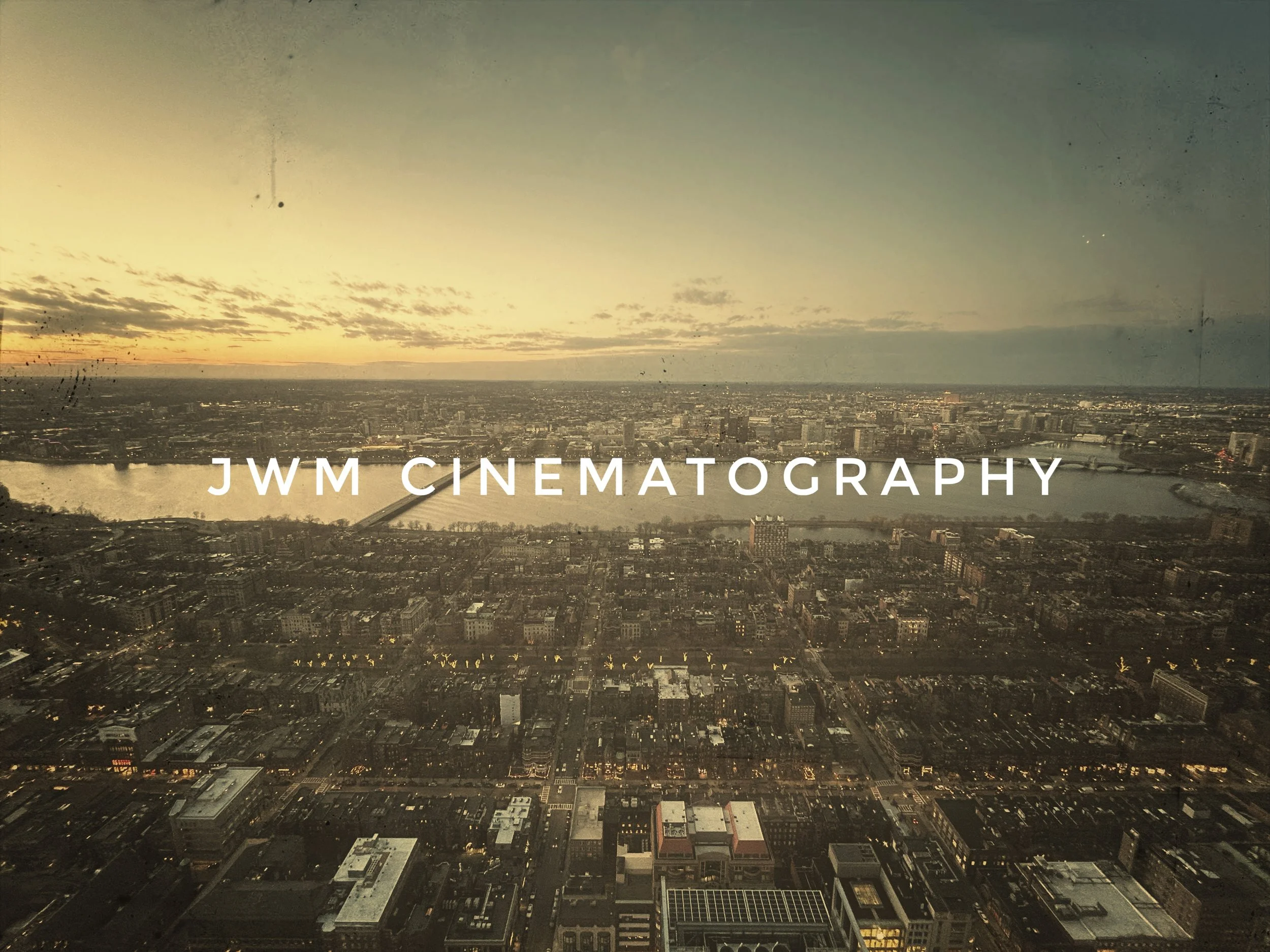 Bird's-eye view of a cityscape at sunset with "JWM Cinematography" text overlay.