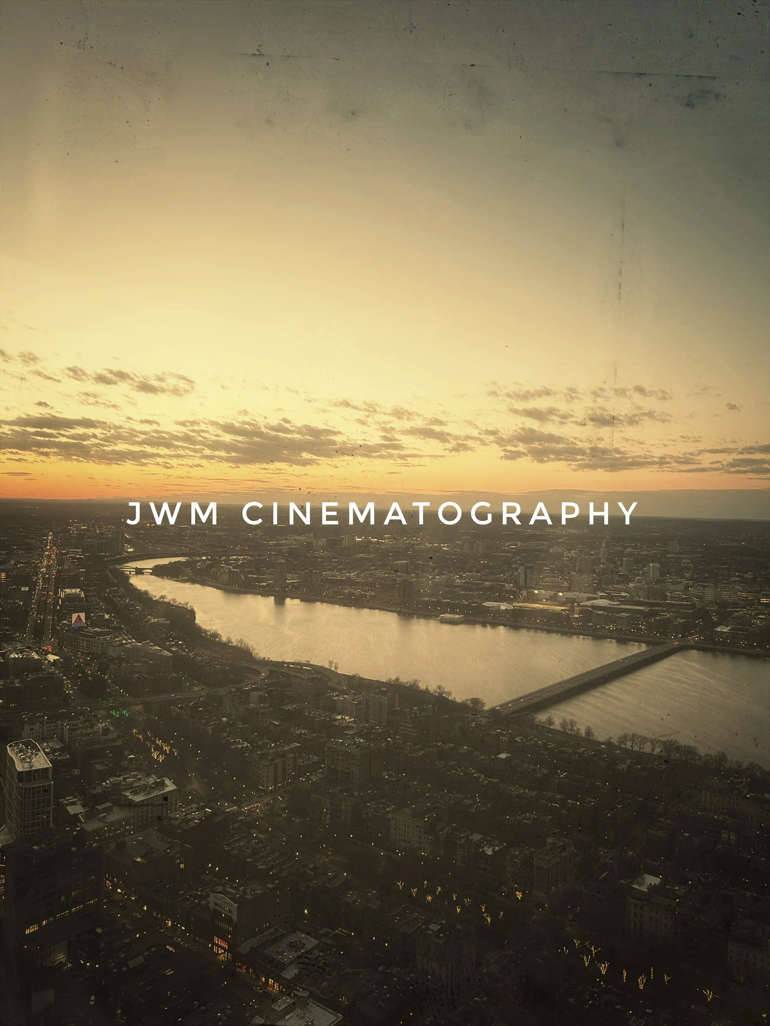 Cityscape at sunset with a river and bridge, labeled 'JWM Cinematography.'