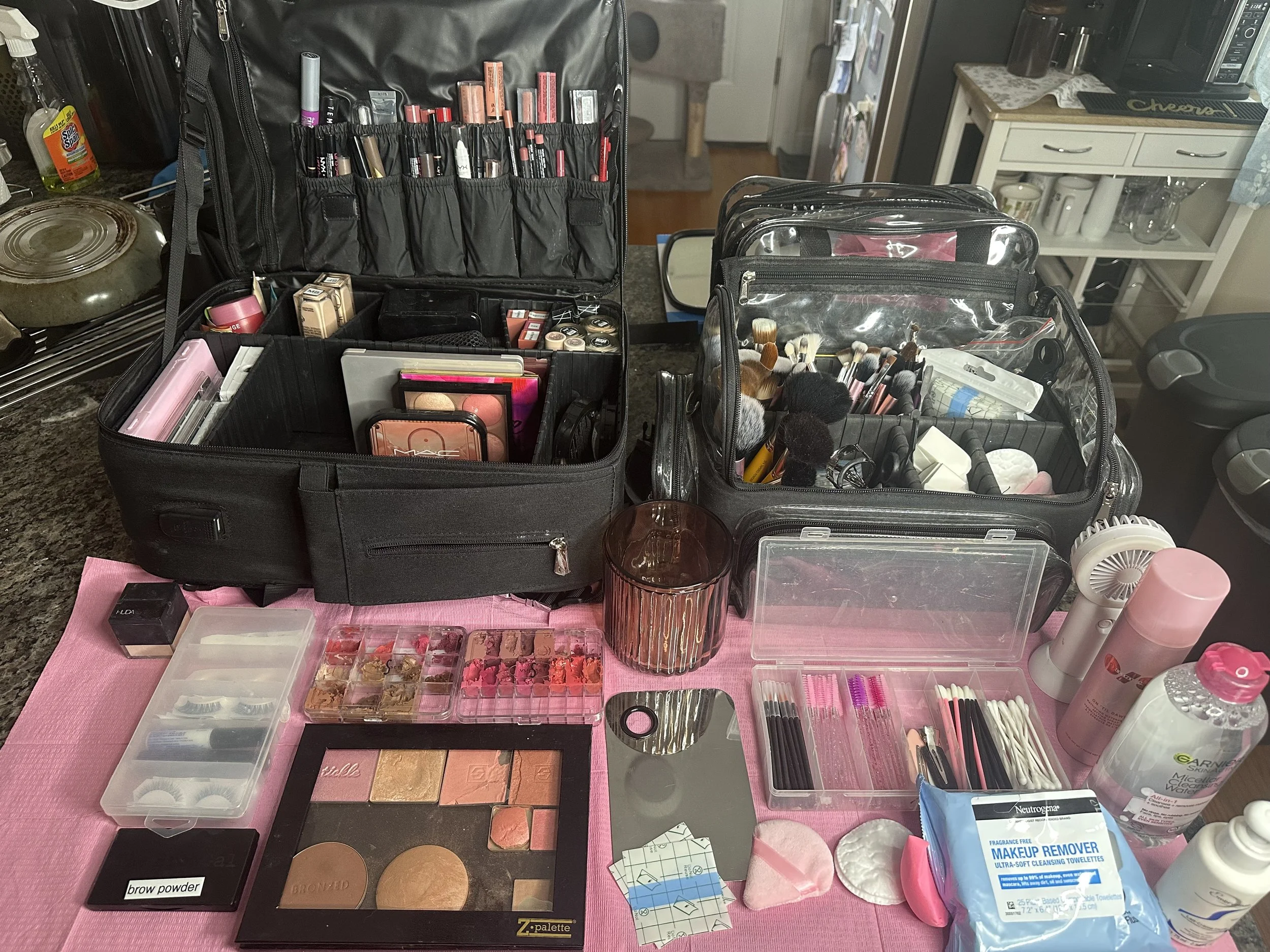 Collection of makeup products including powders, sprays, eyeshadows, and brushes on a white surface.