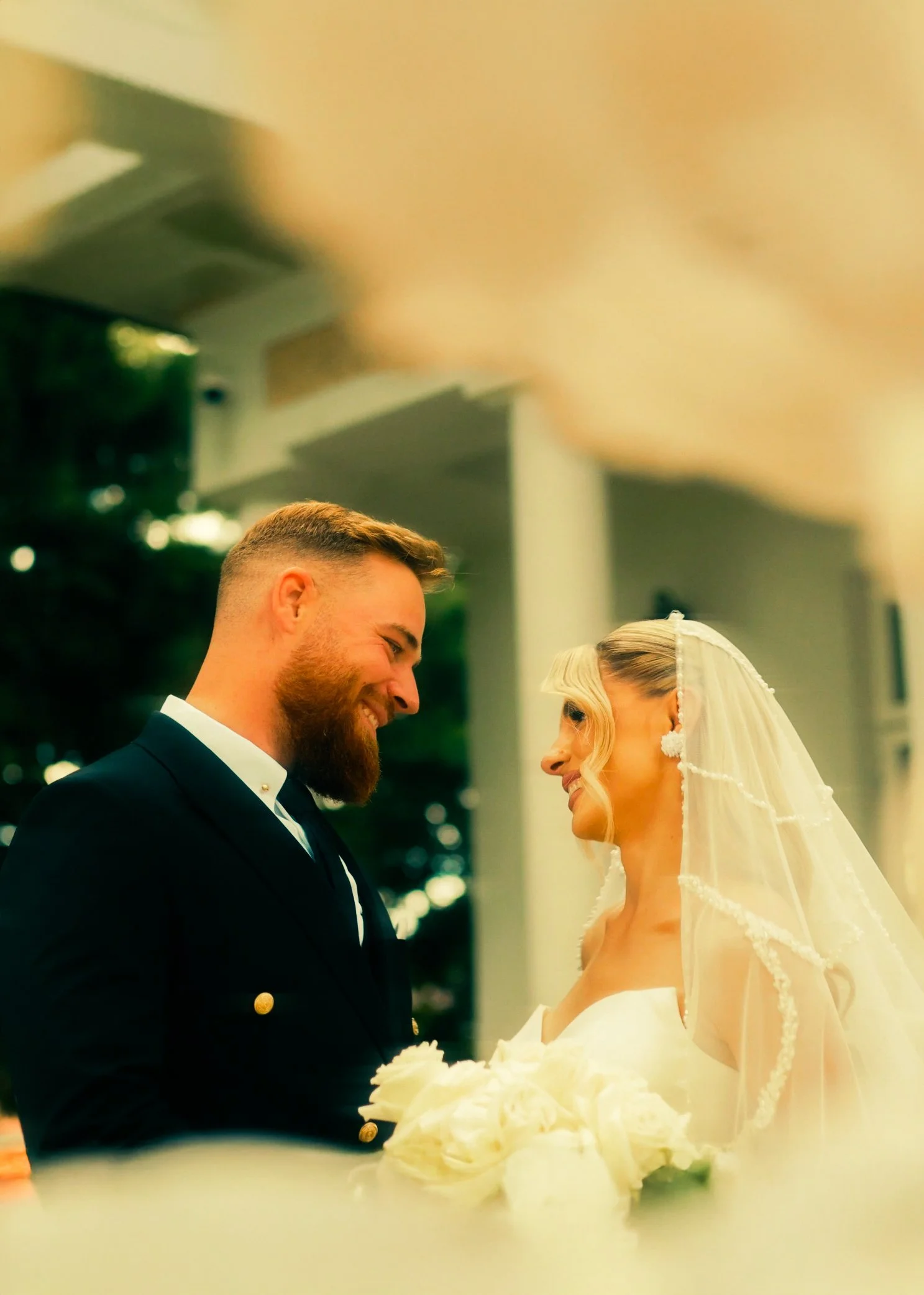 A groom and bride smiling at each other during their wedding celebration.