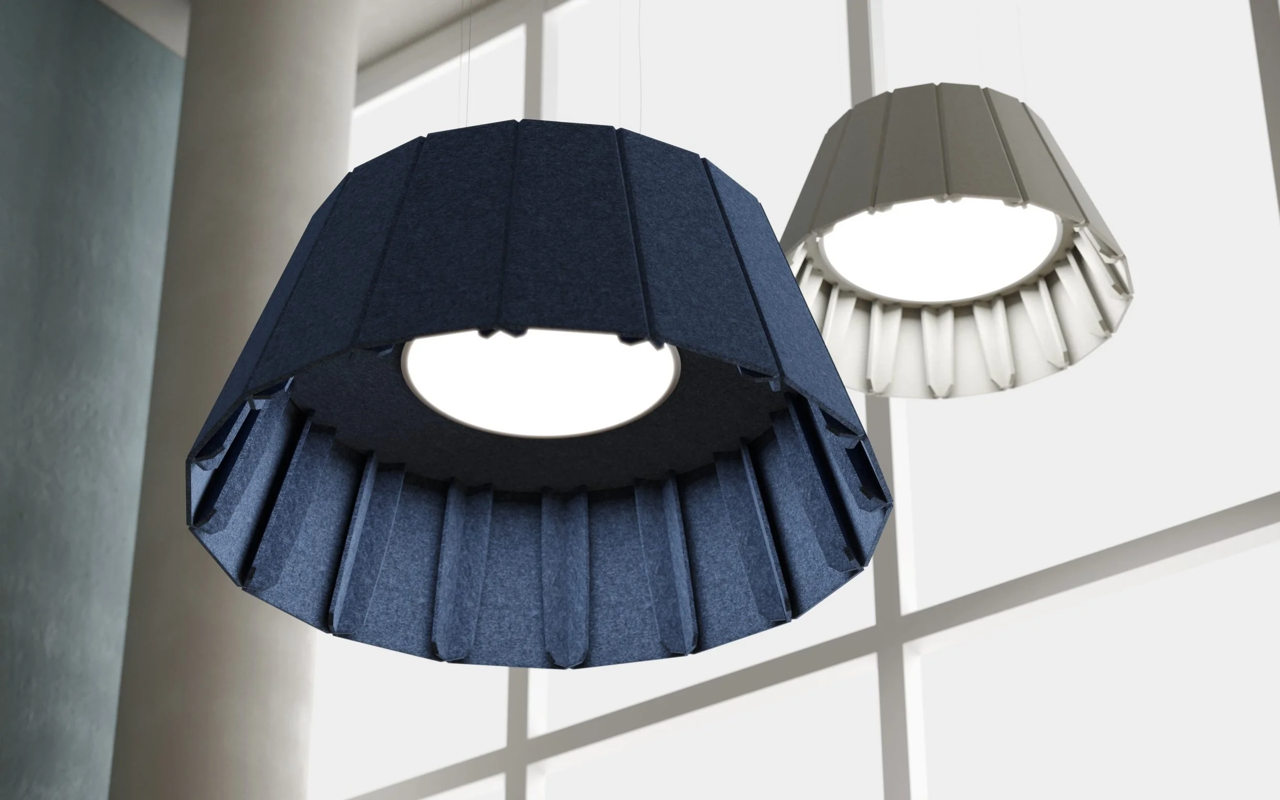 Two hanging lamps with pleated shades, one dark blue and one white, in front of a window with a grid pattern.