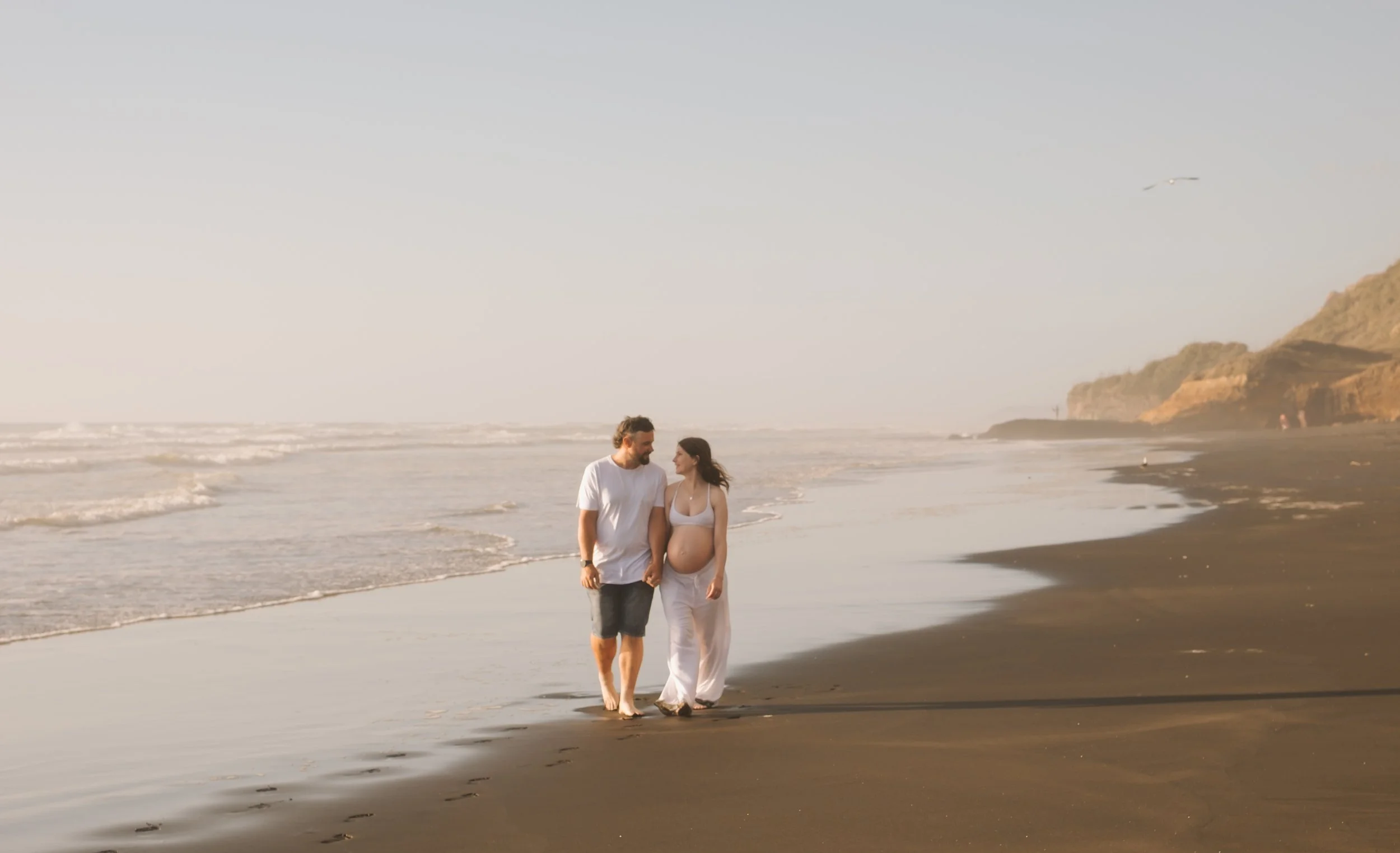 Woman holding a baby in a park with autumn leaves and trees.