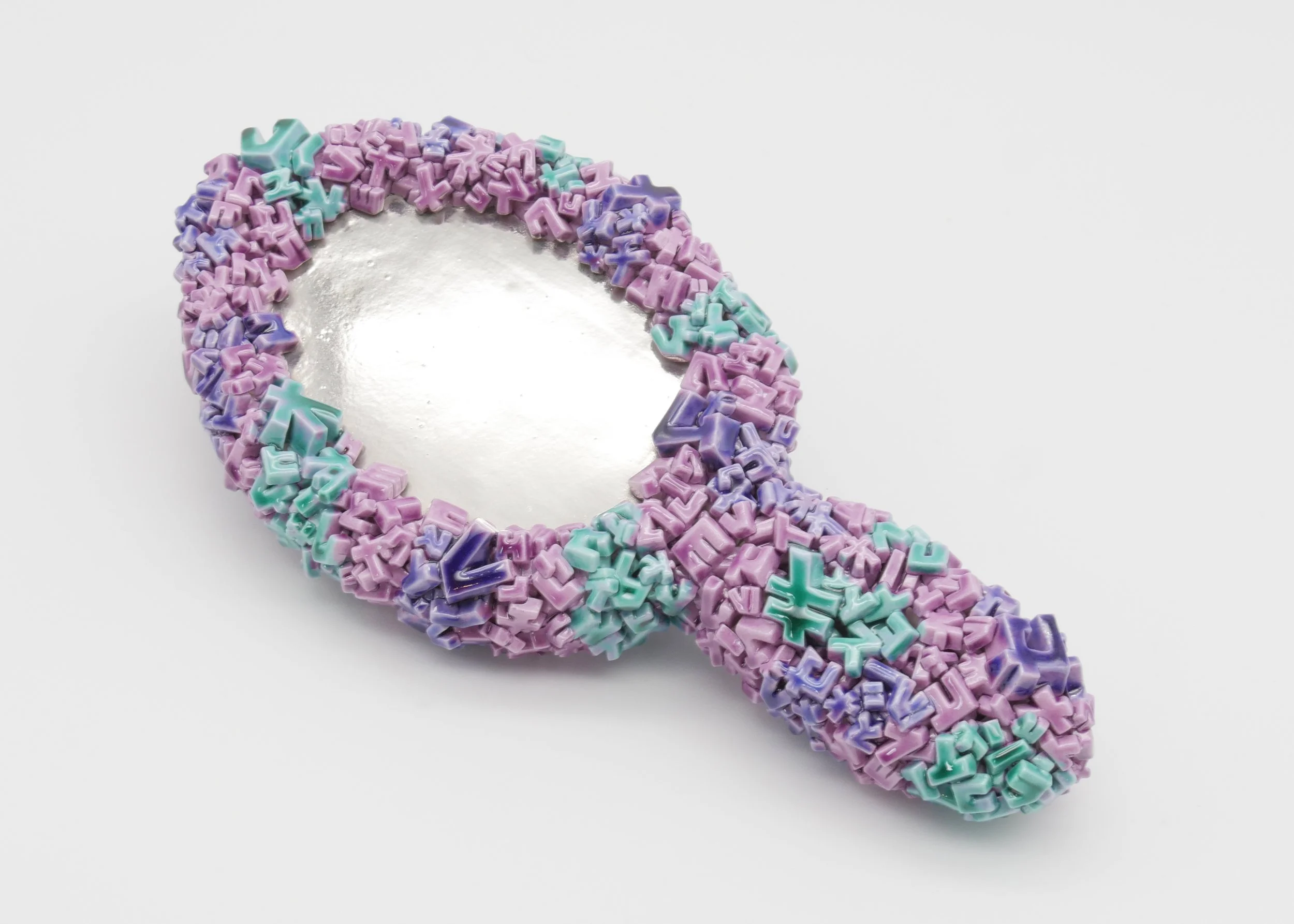 A mirror shaped like an ampersand, decorated with small pastel-colored alphabet-shaped beads in purple, blue, and turquoise.