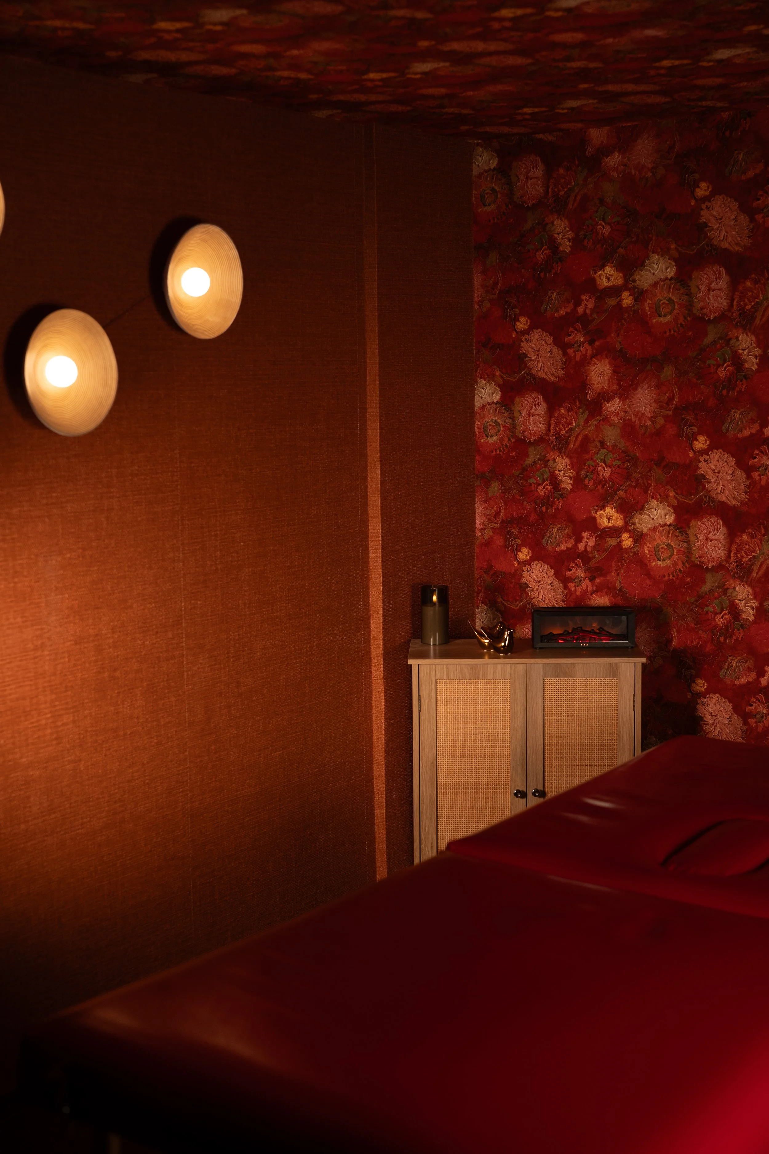 Detail of a red spa treatment room in Mexico with warm lighting and massage table.