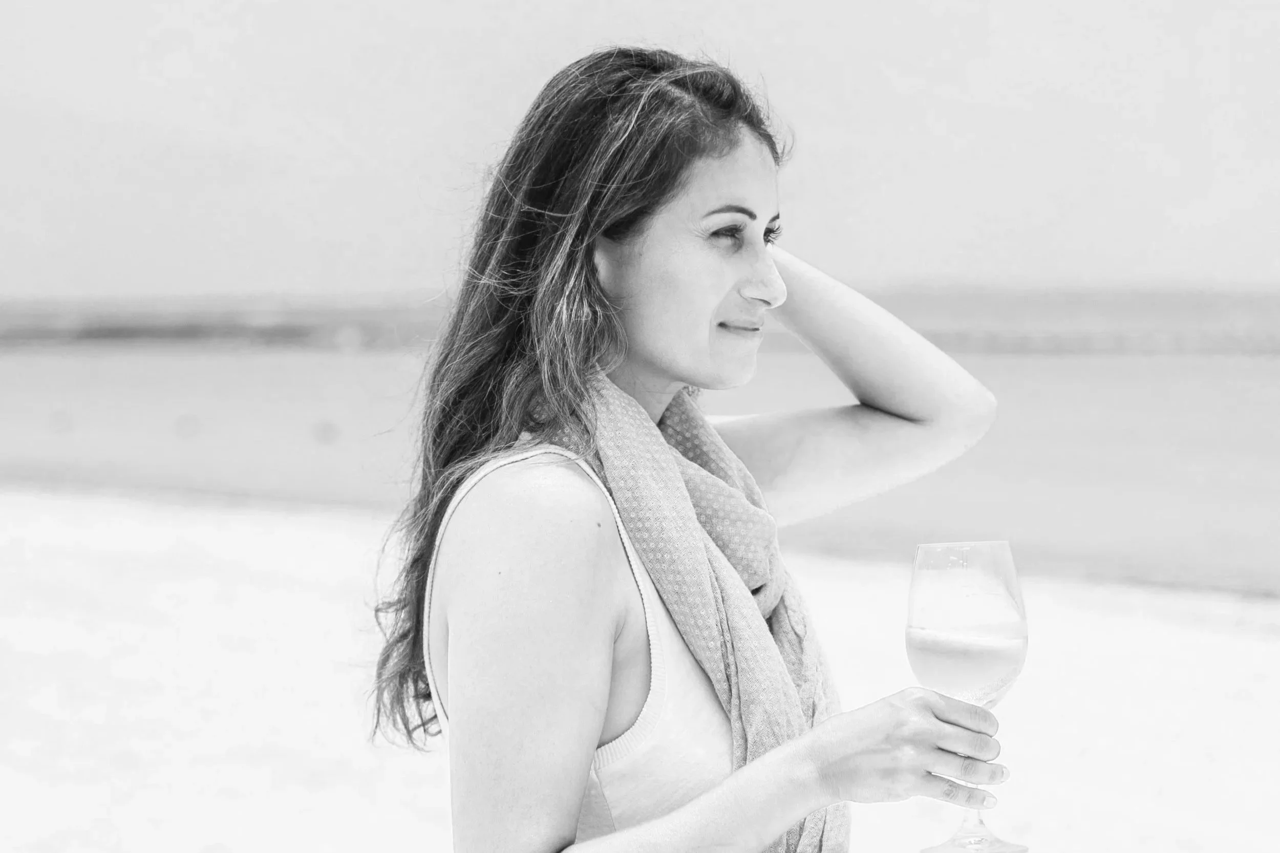 Woman standing on the beach holding a wine glass and reflecting on life, timing, and personal growth.