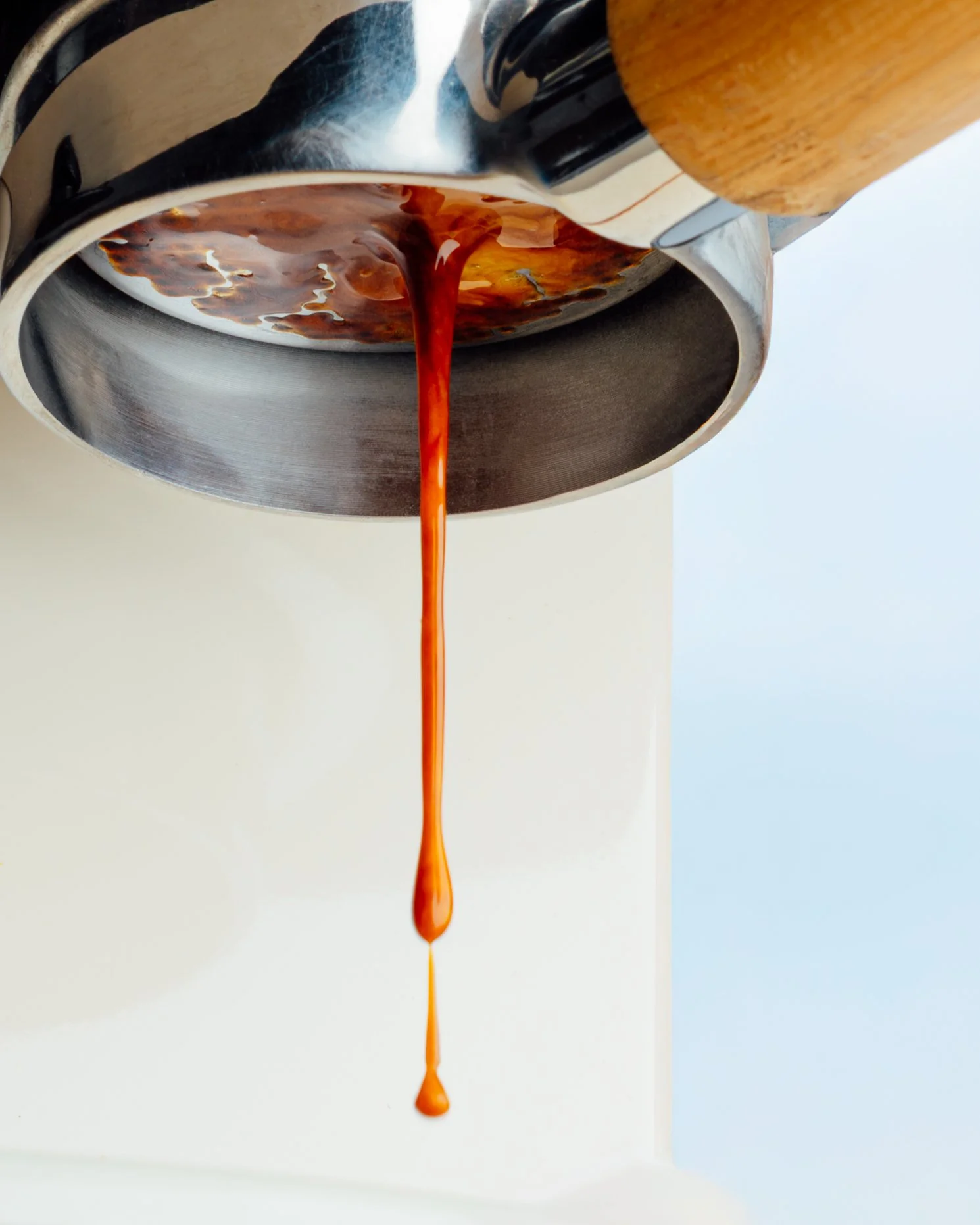 Hot liquid coffee pouring from a coffee maker into a white cup.