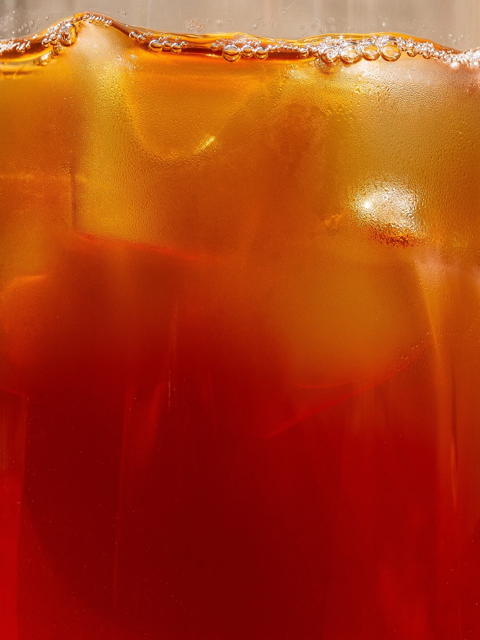 Close-up of a glass of cold brew with condensation and ice cubes, showing bubbles and effervescence.