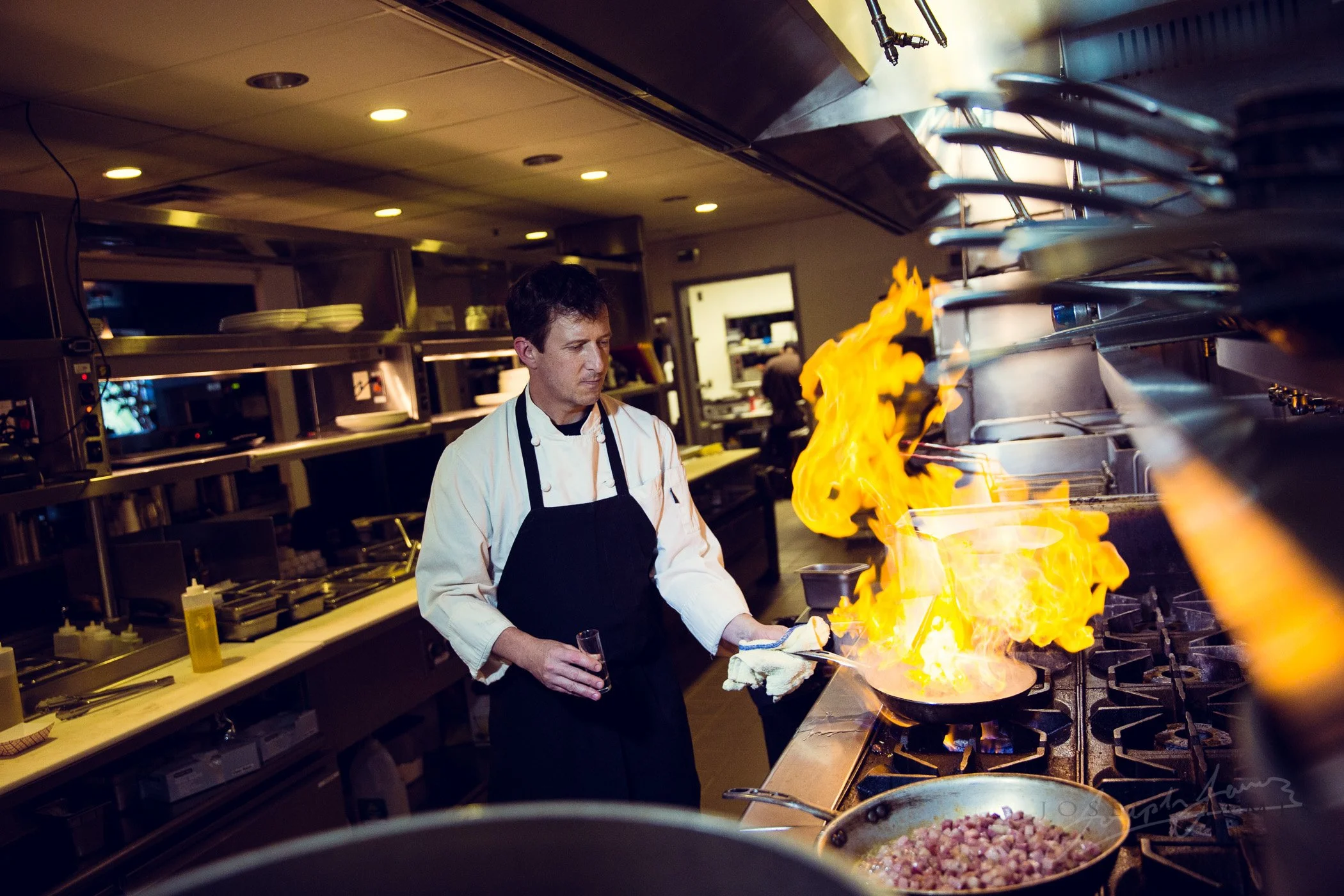 Chef cooking with flames in a professional kitchen.