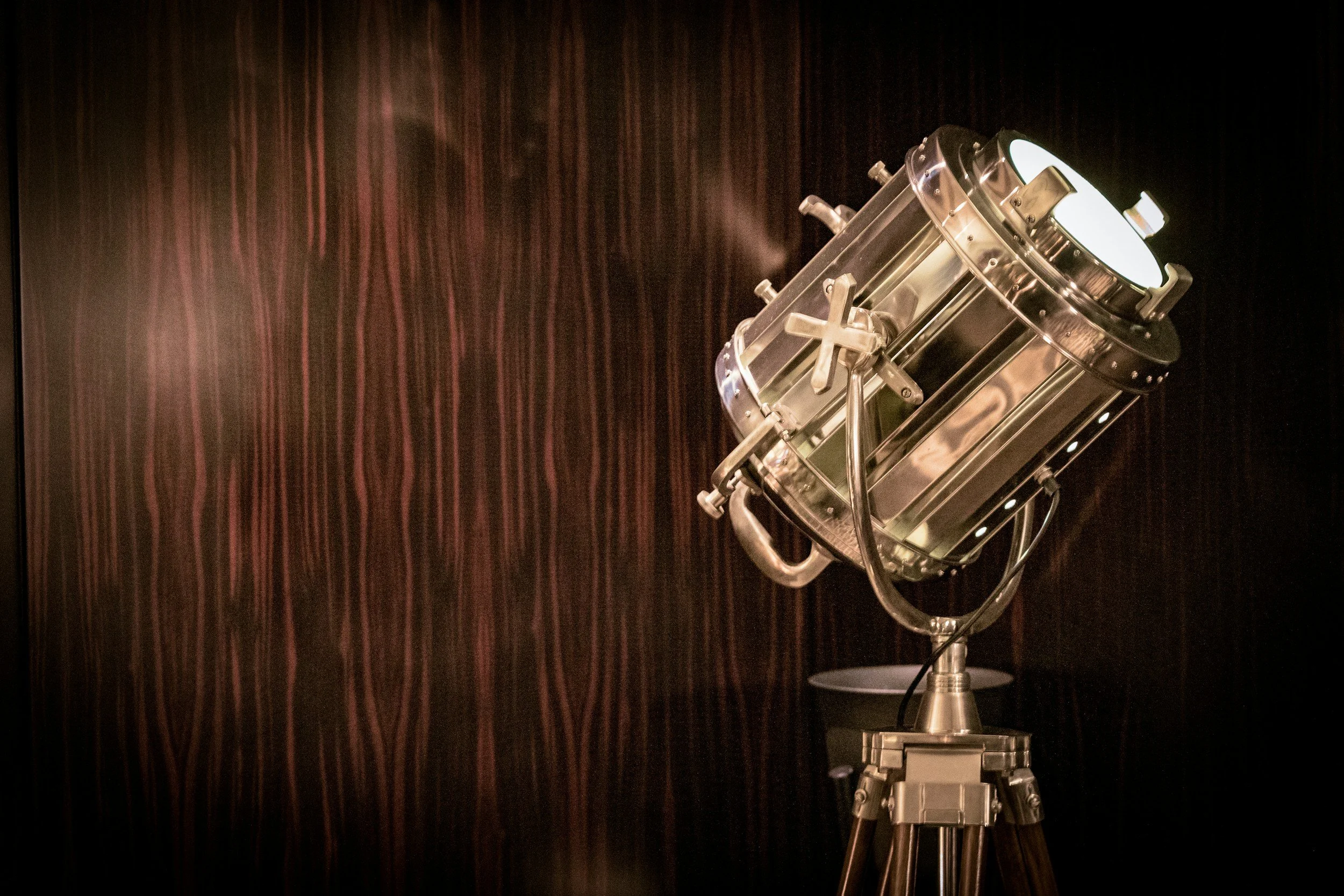 Vintage metal spotlight on tripod with dark wooden background