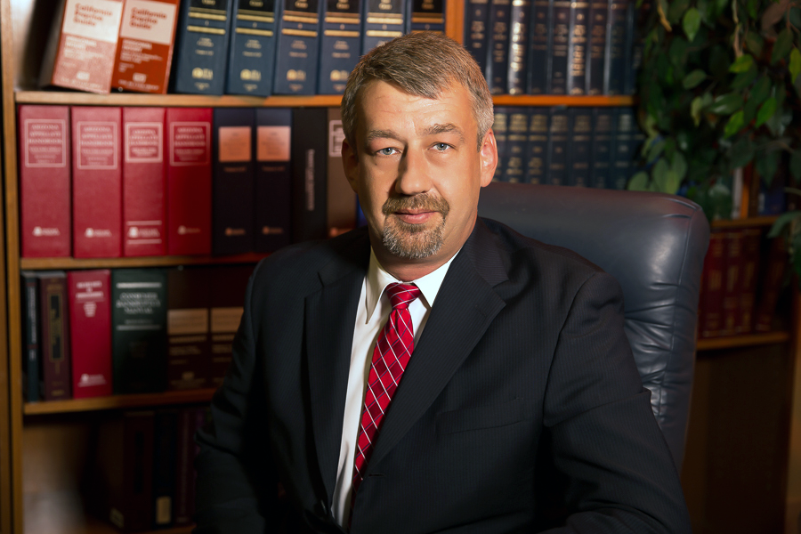 Man in suit seated in an office with law books on shelves