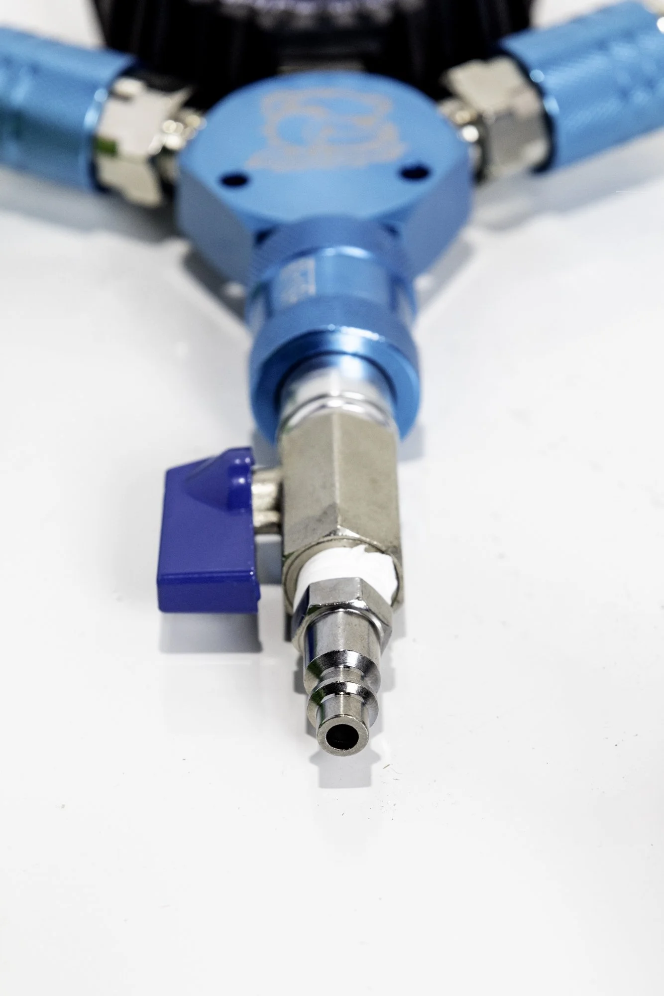 Close-up of a blue and silver air pressure regulator with a valve and fittings on a white background.