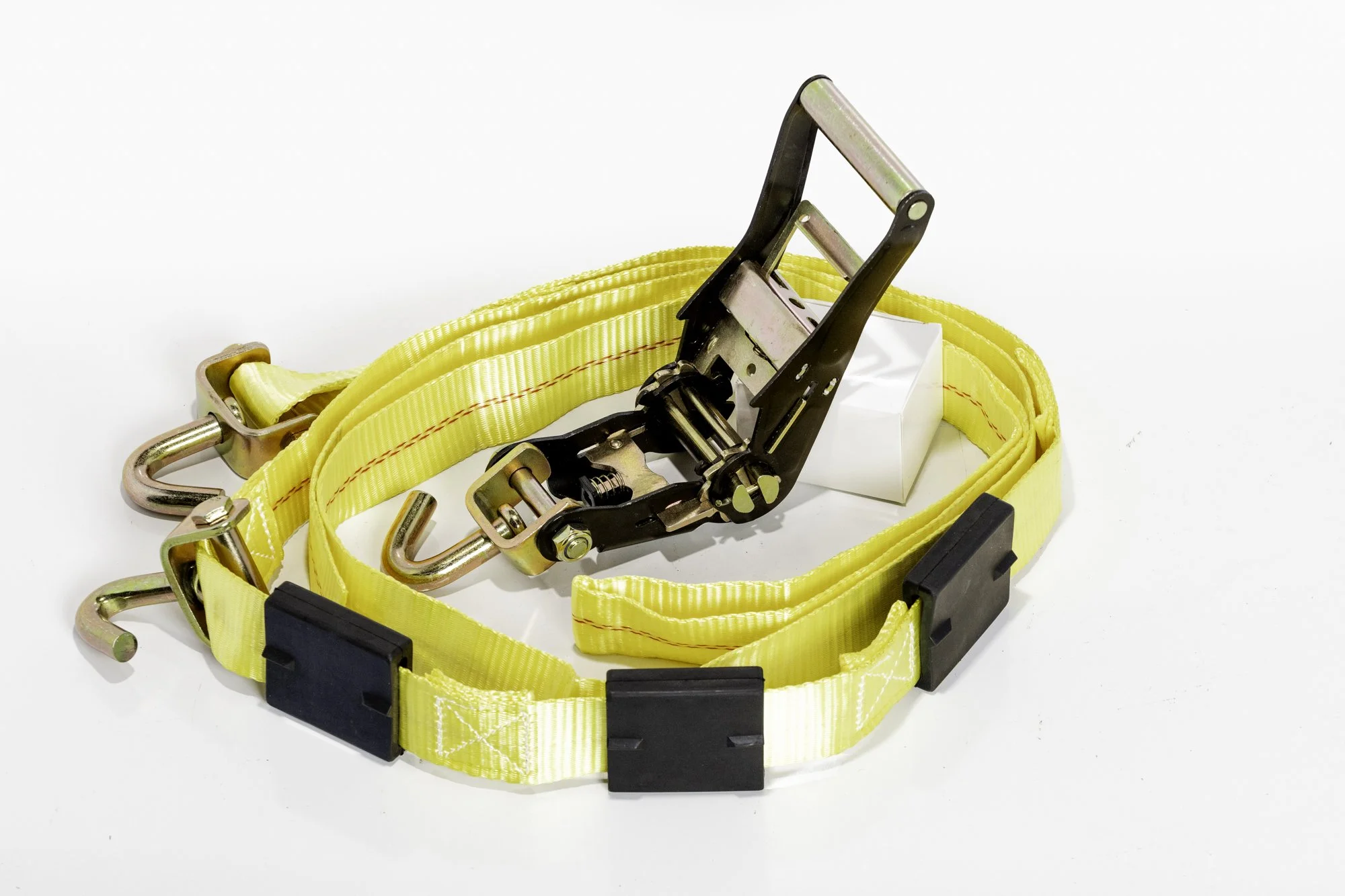 Yellow ratchet tie-down strap with metal hooks on a white background.