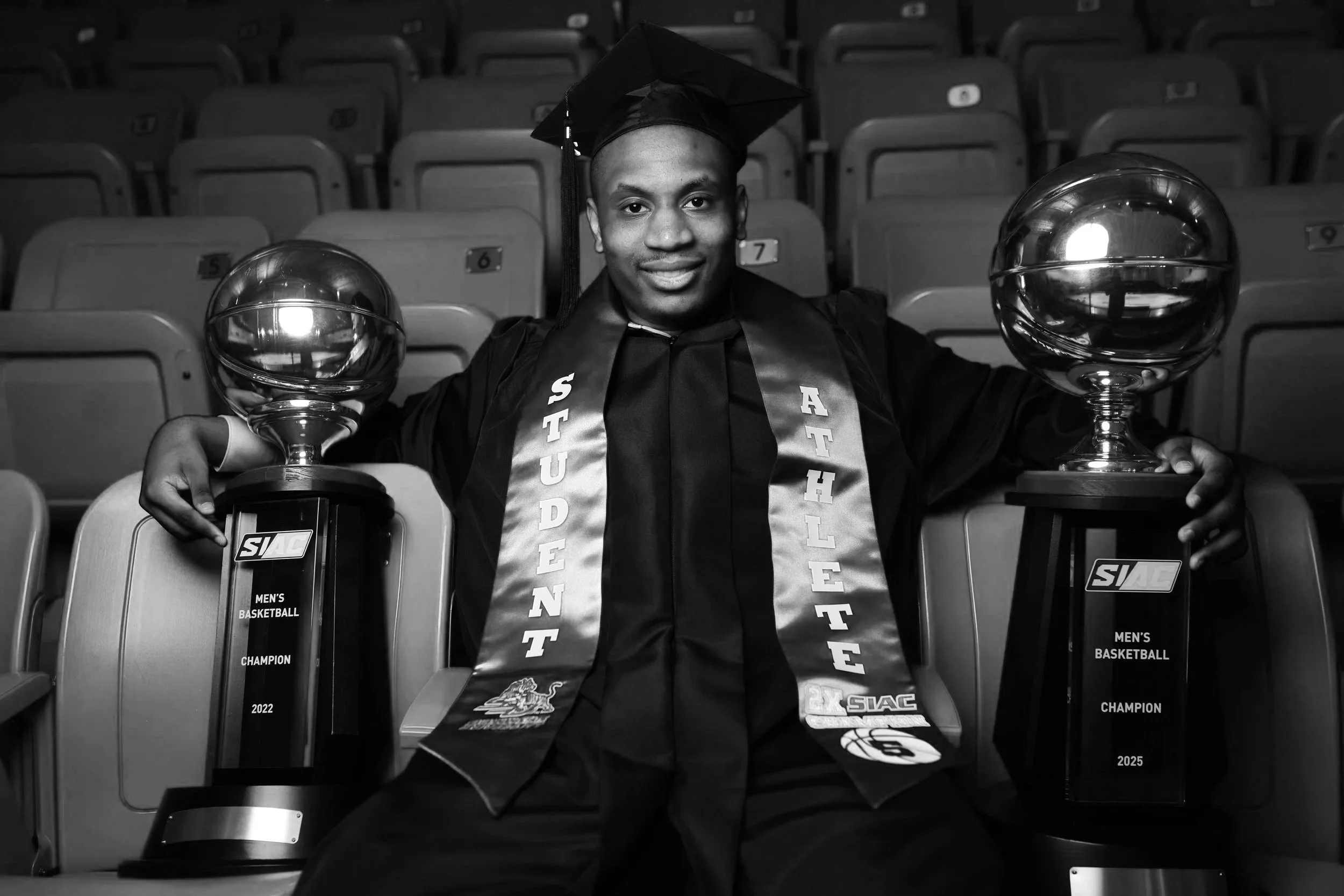 Graduation ceremony with four people, one wearing cap and gown holding a diploma, standing with family.
