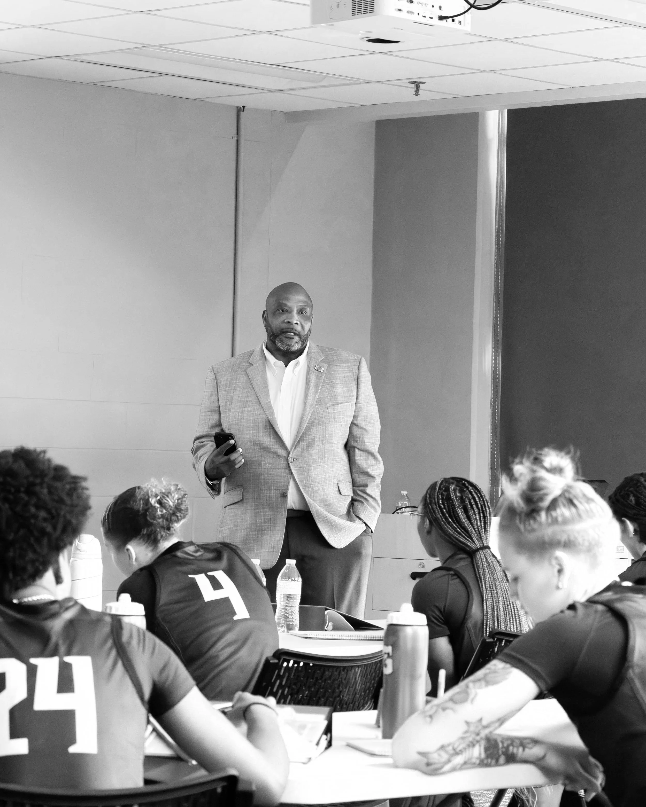 Two men taking a mirror selfie in a gym, with workout equipment and a blue and white abstract wall design behind them.