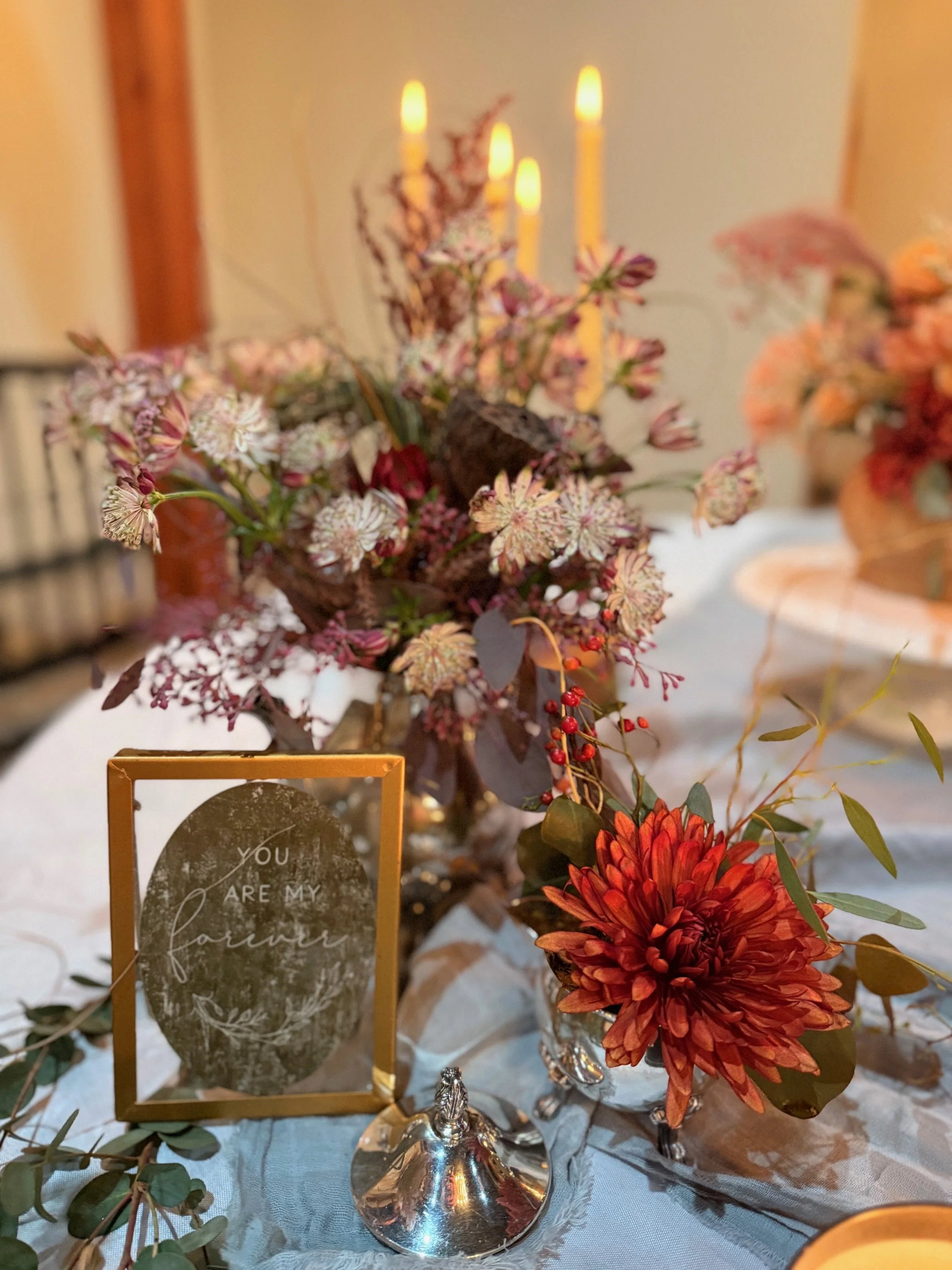 A decorated table with a floral centerpiece, candles, and a greeting card that says "You are my forever."