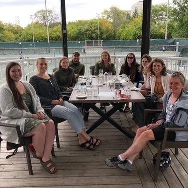 Nine lab members sat around a table outdoors