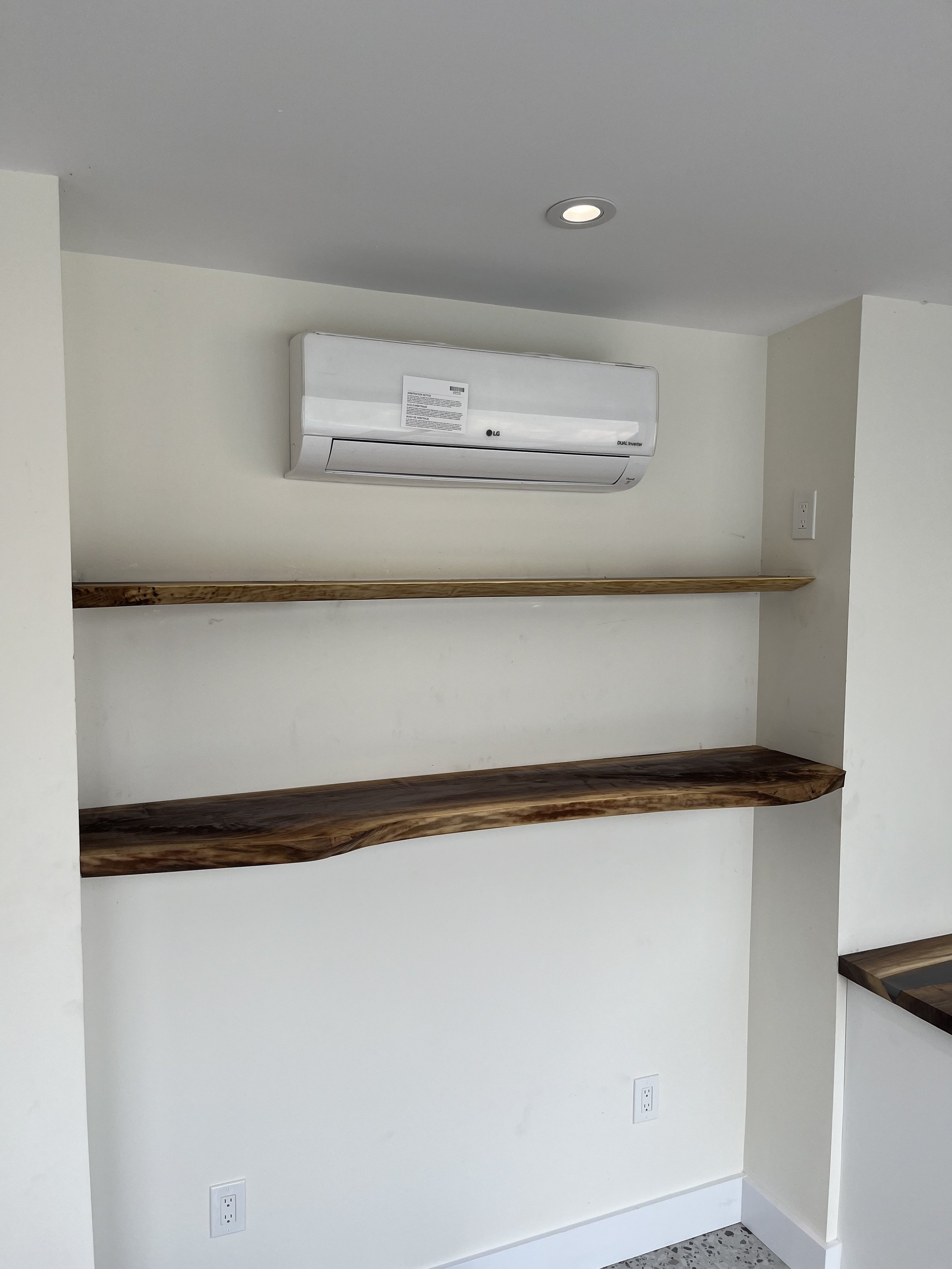 Wall with mounted air conditioning unit and wooden shelves