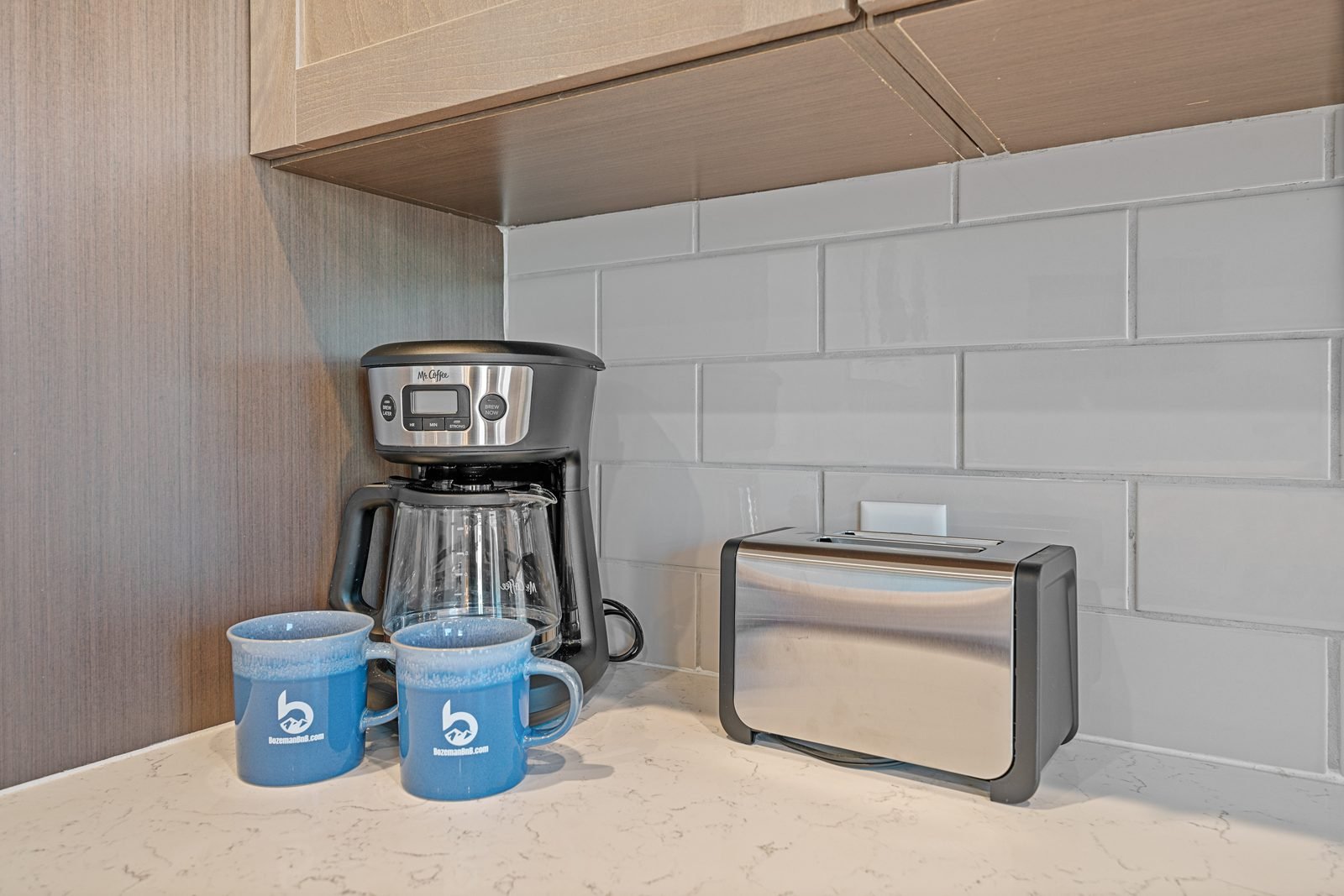 Coffee maker and two BozemanBnB branded mugs set out on the counter of a managed rental.